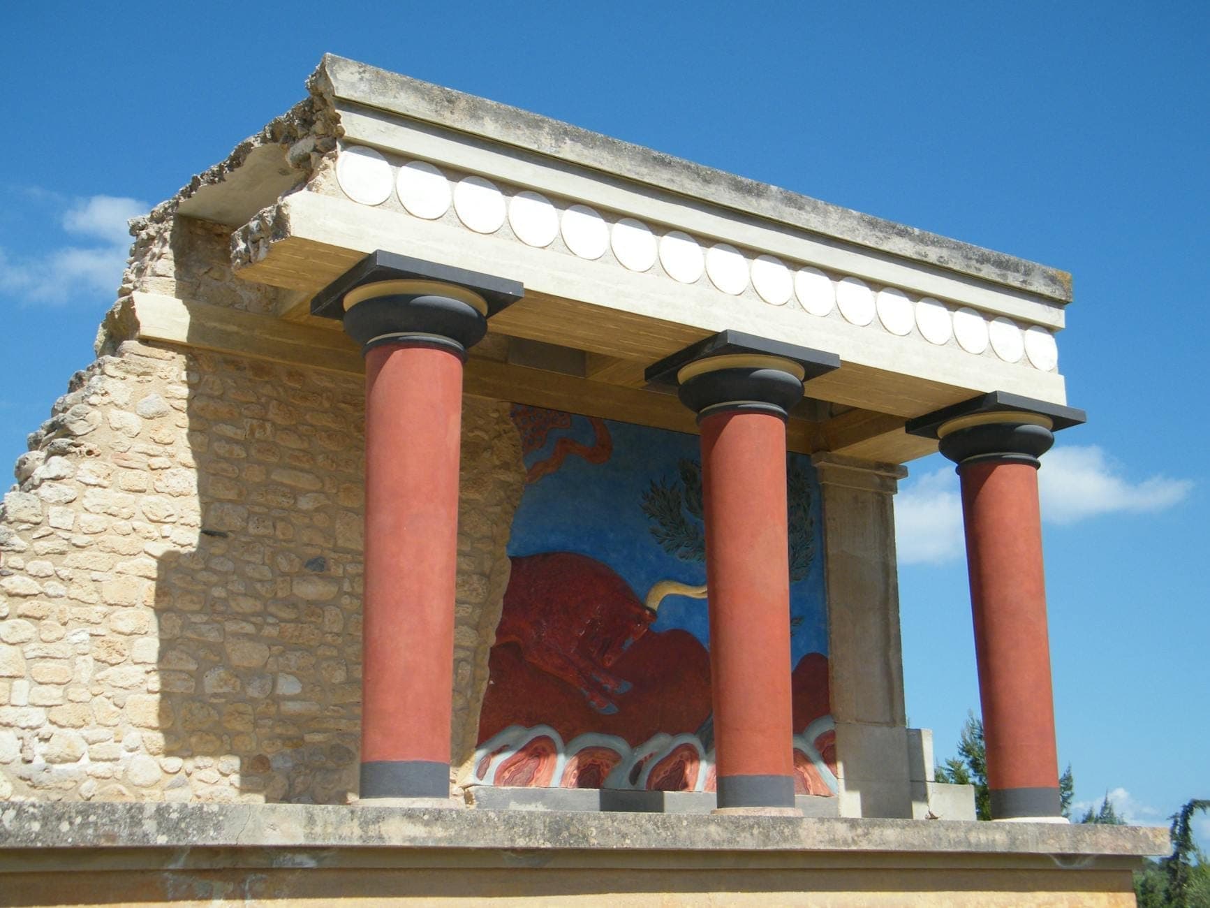 Teilansicht der farbenfrohen Ruinen und Fresken des Palastes von Knossos unter blauem Himmel, eine ikonische archäologische Stätte in der Nähe von Weingütern auf Kreta.