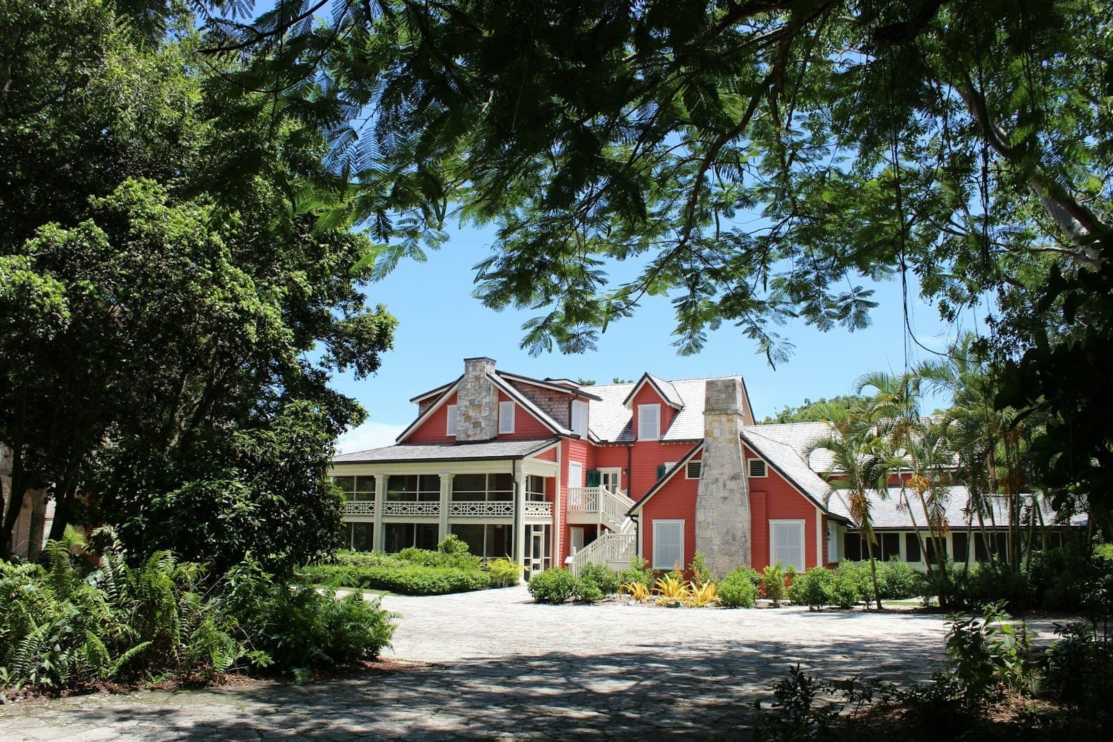 Historic 1920s-era red and white building at Deering Estate surrounded by lush trees and greenery under a clear blue sky, evoking Miami’s hidden natural charm.