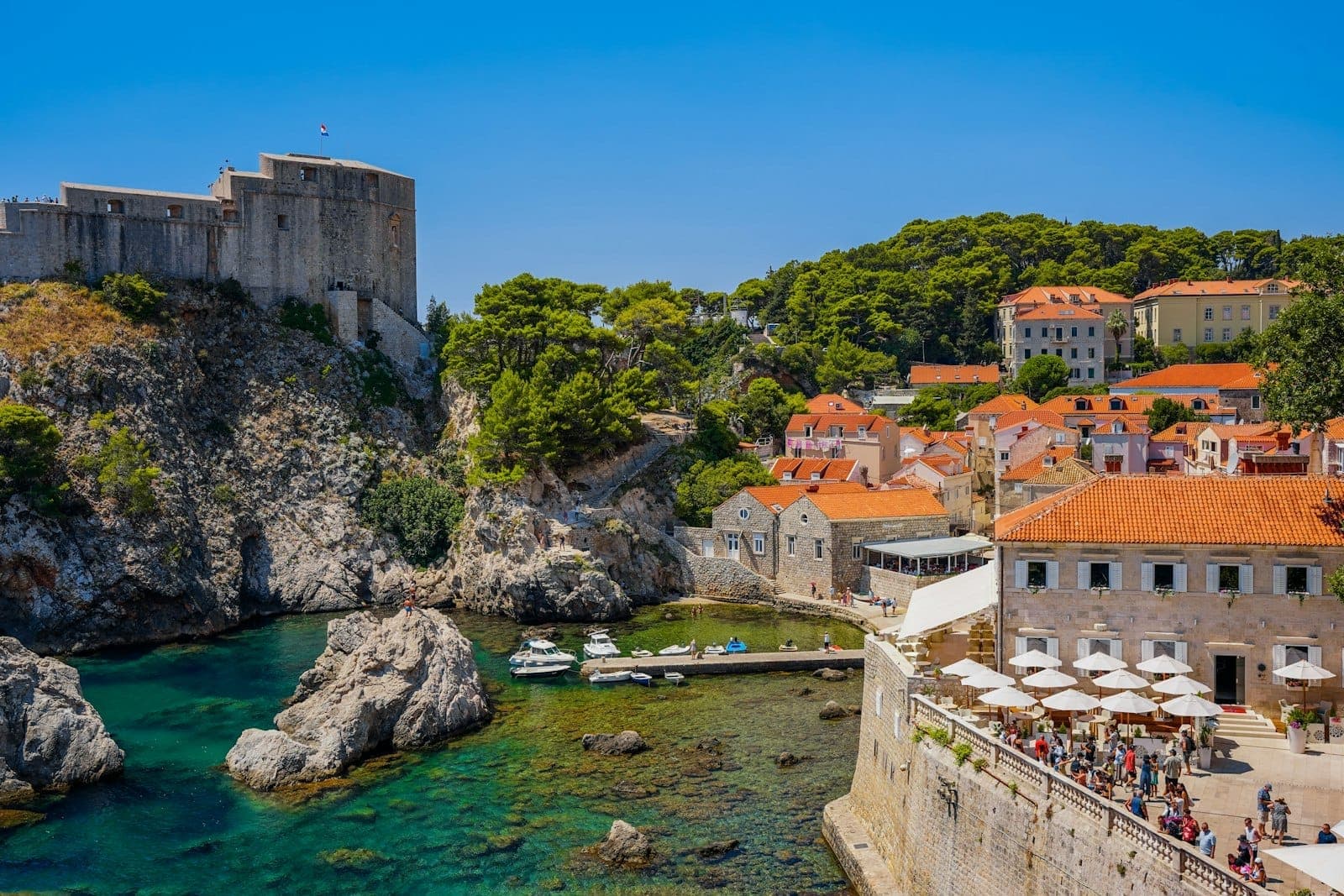Blick auf die alte Stadtmauer von Dubrovnik mit Touristen in der Nähe des Pile-Tors und Straßencafés – ein typischer Ort zum Kauf oder zur Aktivierung des City Pass.