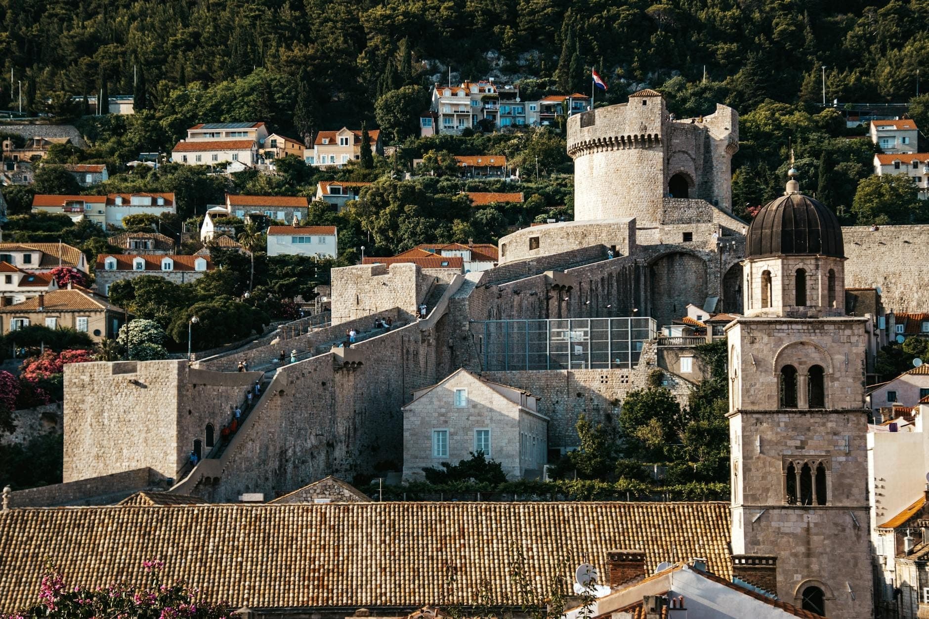 Крупный план городских стен Дубровника с башней Минчета и куполом расположенной рядом церкви — классические достопримечательности маршрута по стенам.