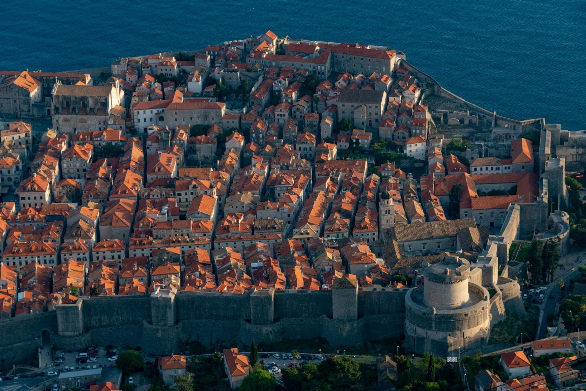 Luftaufnahme der historischen Altstadt von Dubrovnik mit ihren Steinmauern und orangefarbenen Dächern am Adriatischen Meer.