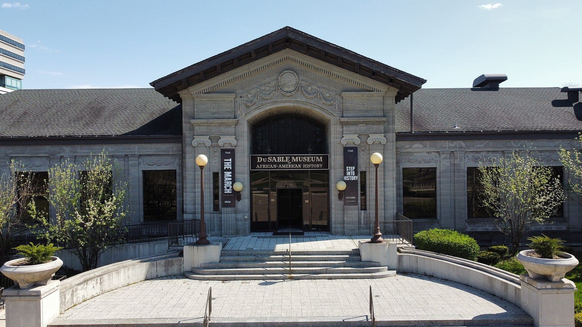 Entrada principal del DuSable Museum of African-American History con arquitectura clásica de piedra, escalones curvos y jardines verdes en un día despejado.