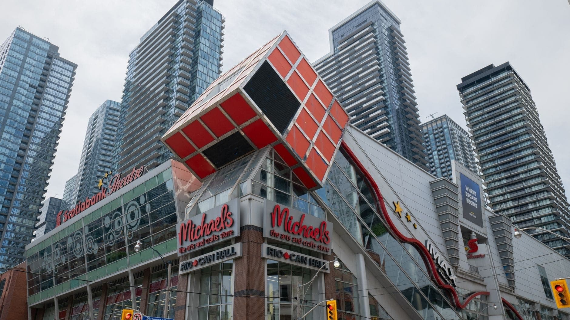 Vista stradale dell'edificio Scotiabank Theatre di Toronto con la sua gigantesca facciata a cubo rosso, circondato da moderni condomini di grandi altezze sotto un cielo nuvoloso nell'Entertainment District di Toronto.
