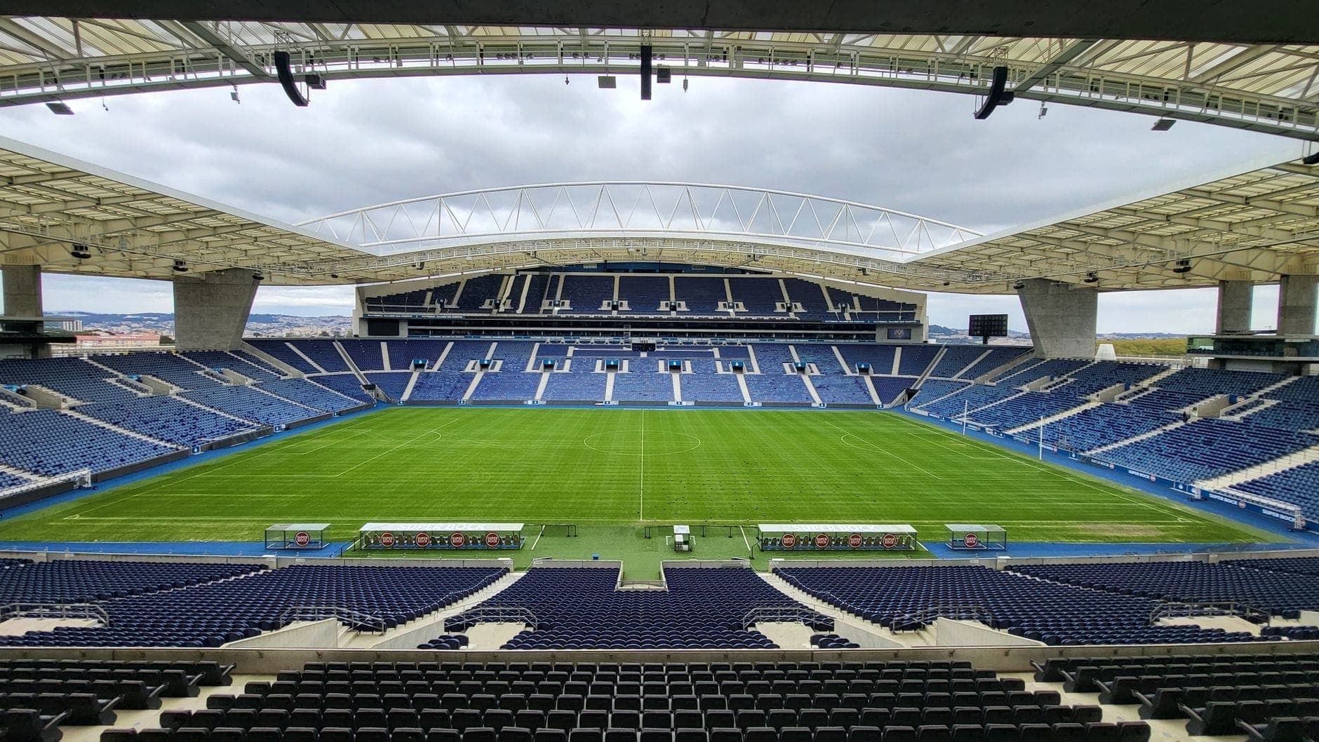 Weitwinkelpanorama des leeren Estádio do Dragão mit Blick auf den Rasen, die modernen Tribünen und die geschwungene Dachkonstruktion unter bewölktem Himmel.