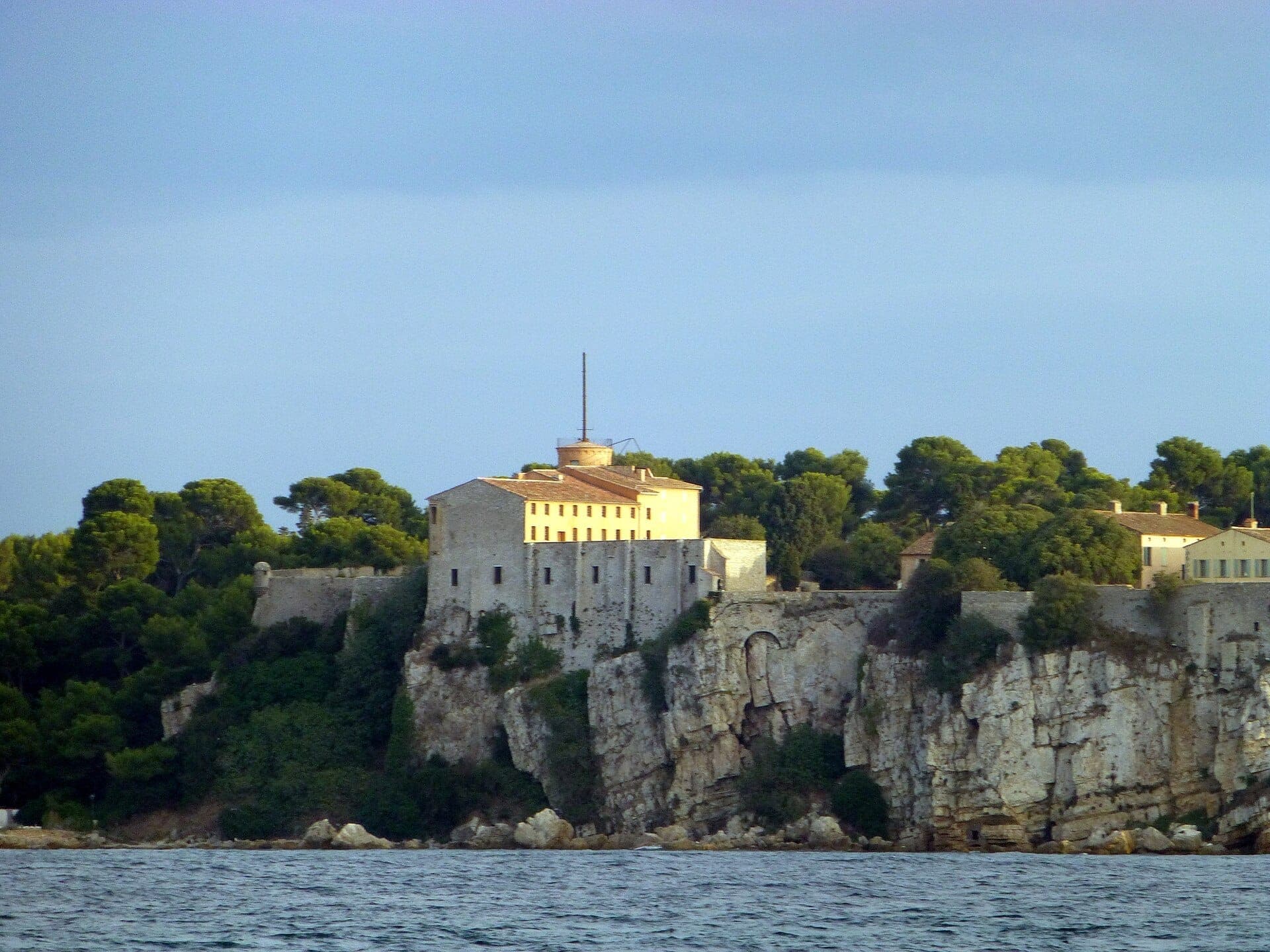 Fort Royal, возвышающийся на вершине скалистых утёсов на острове Île Sainte-Marguerite, окружённый густыми соснами и overlooking синие воды Средиземного моря.