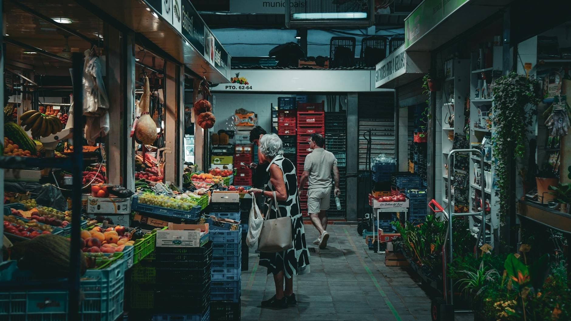 Überdachter Markt mit buntem Obst und Gemüse, Einkäufern an den Ständen und natürlichen lokalen Produkten in einer lebhaften Atmosphäre.