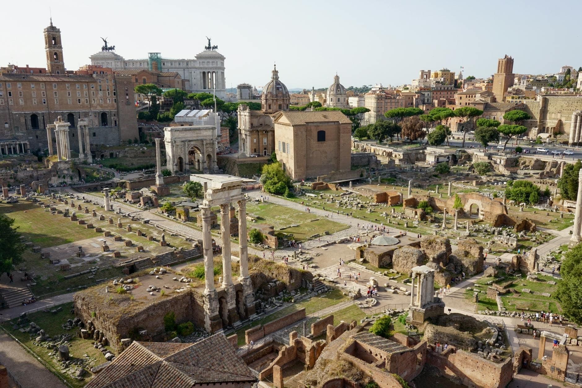 Vue panoramique des ruines du Forum Romain avec des colonnes antiques, des temples et des bâtiments historiques au centre de Rome par une journée ensoleillée.