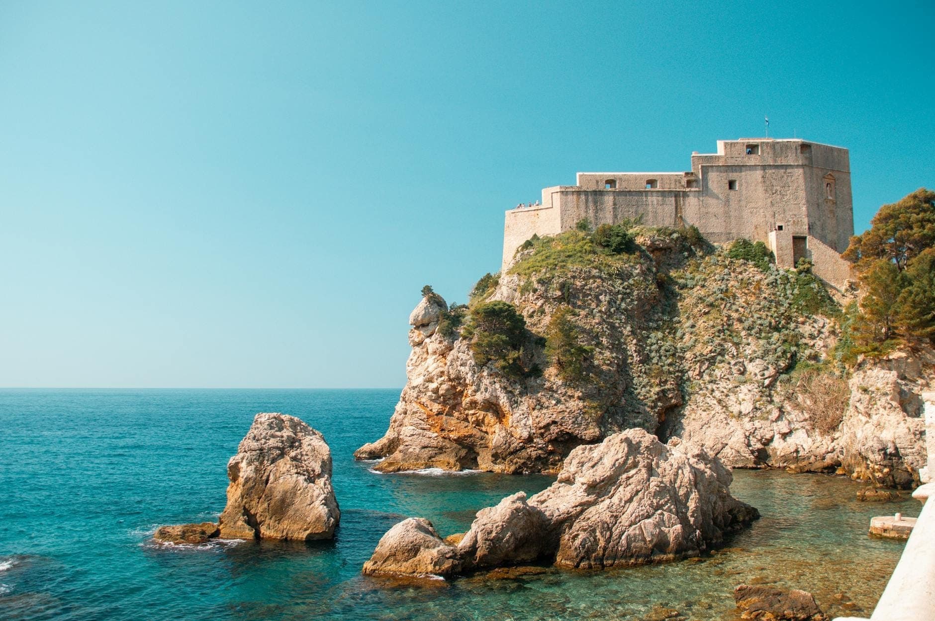 Fort Lovrijenac thront auf einem felsigen Kliff über dem klaren blauen Adriatischen Meer unter einem hellen, sonnigen Himmel in Dubrovnik, Kroatien.