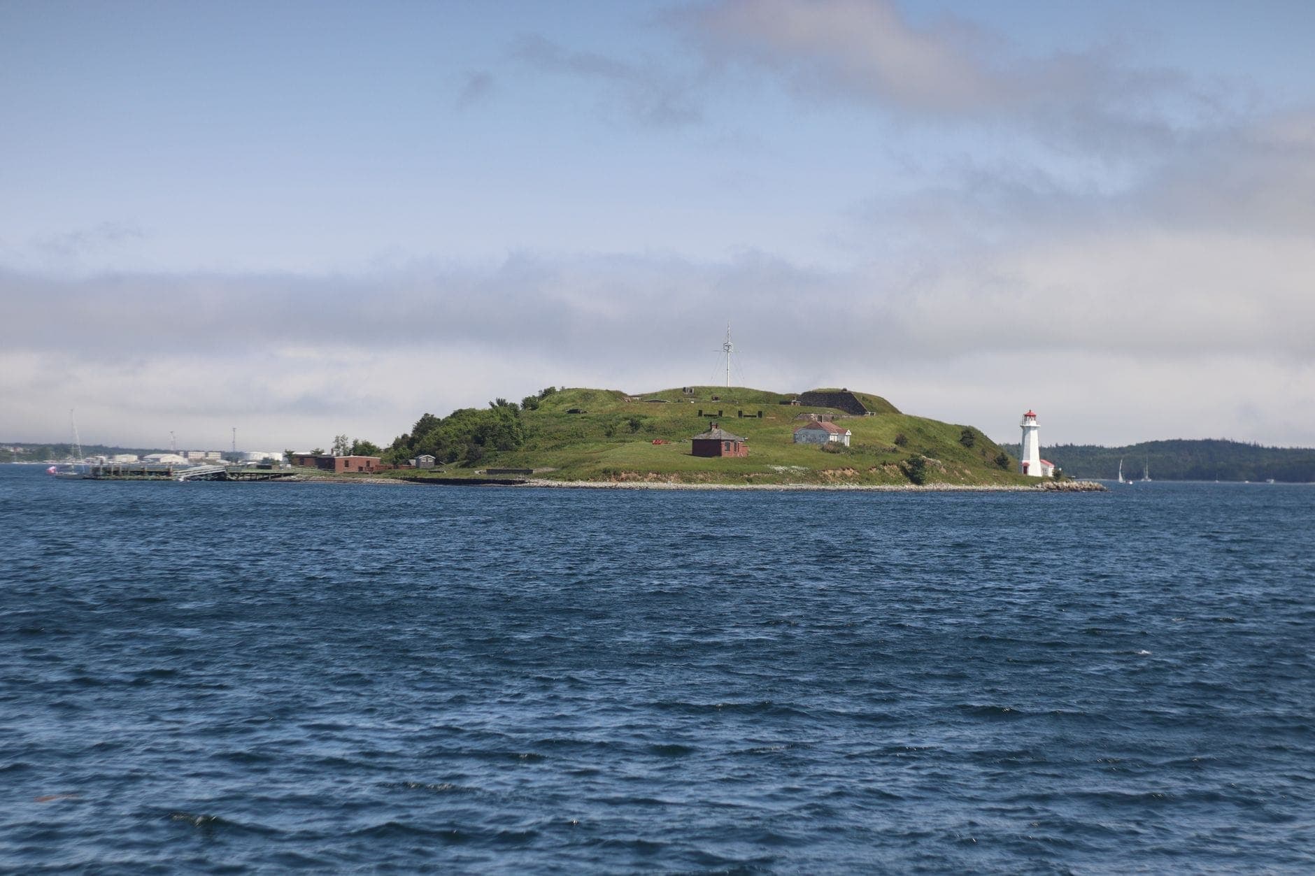 Vue d'ensemble de Georges Island dans le port de Boston : paysage herbeux, bâtiments historiques du fort, eaux bleues environnantes et ciel dégagé en plein jour.