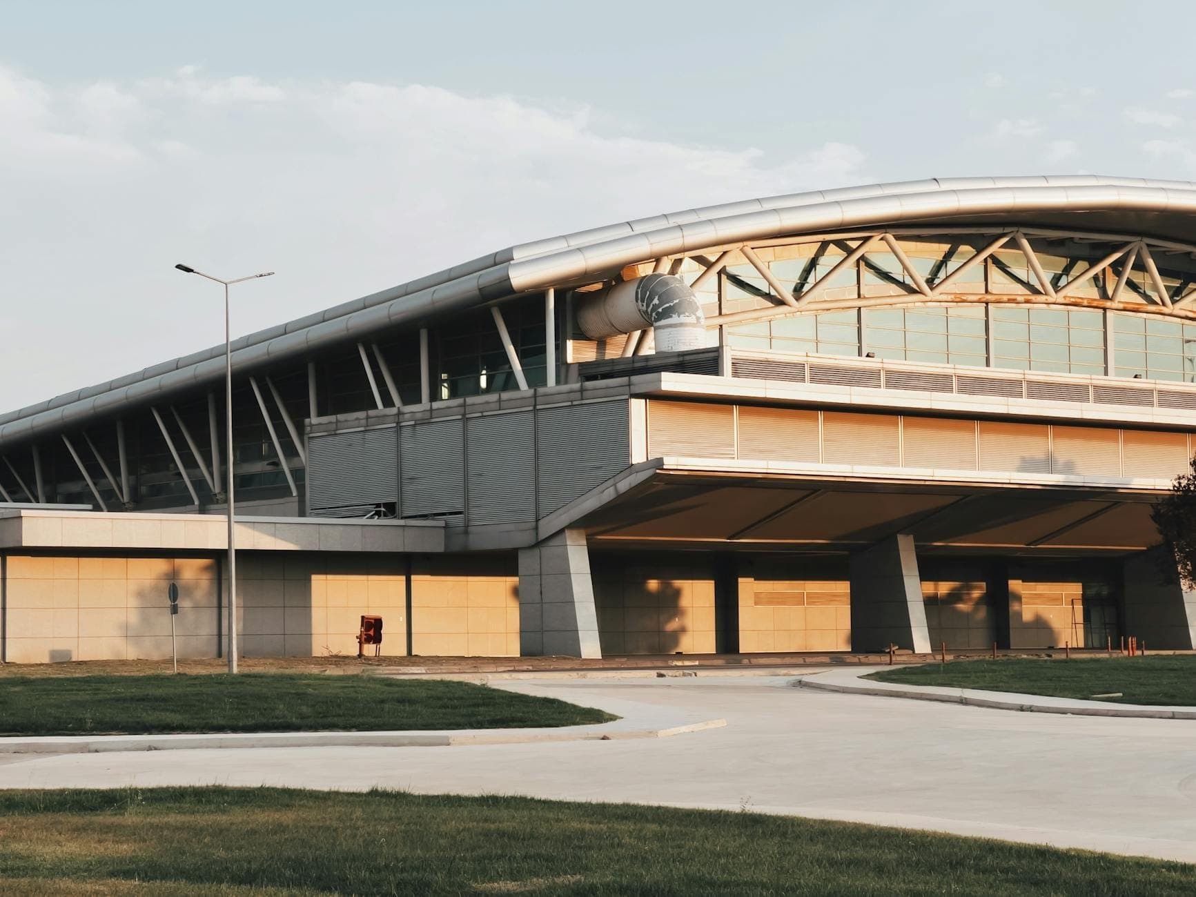 Außenansicht eines modernen Flughafenterminals in der Abenddämmerung mit gebogenem Dach und breitem Eingang, wahrscheinlich der Flughafen Dubrovnik.