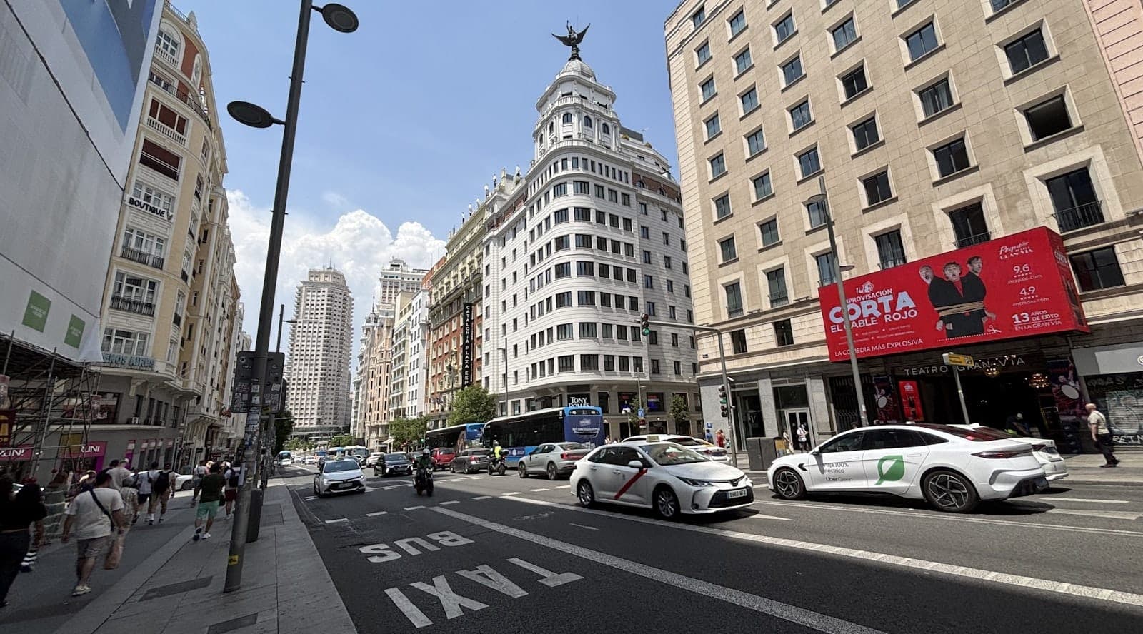 Concurrida calle de Madrid con taxis blancos marcados con una franja roja, monumentos de la ciudad y un carril exclusivo para taxis, mostrando las opciones de transporte local.