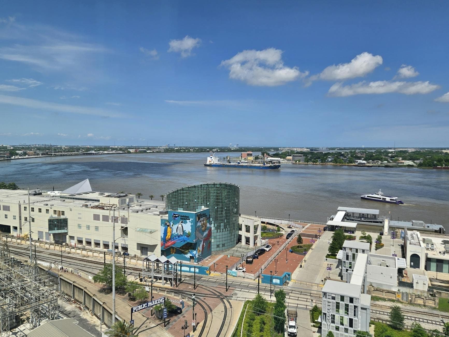 วิวของแม่น้ำ Mississippi ริมน้ำ New Orleans เรือเฟอร์รี่ และรางรถราง ในวันที่ท้องฟ้าแจ่มใสพร้อมสถานที่สำคัญของเมืองที่มองเห็นได้