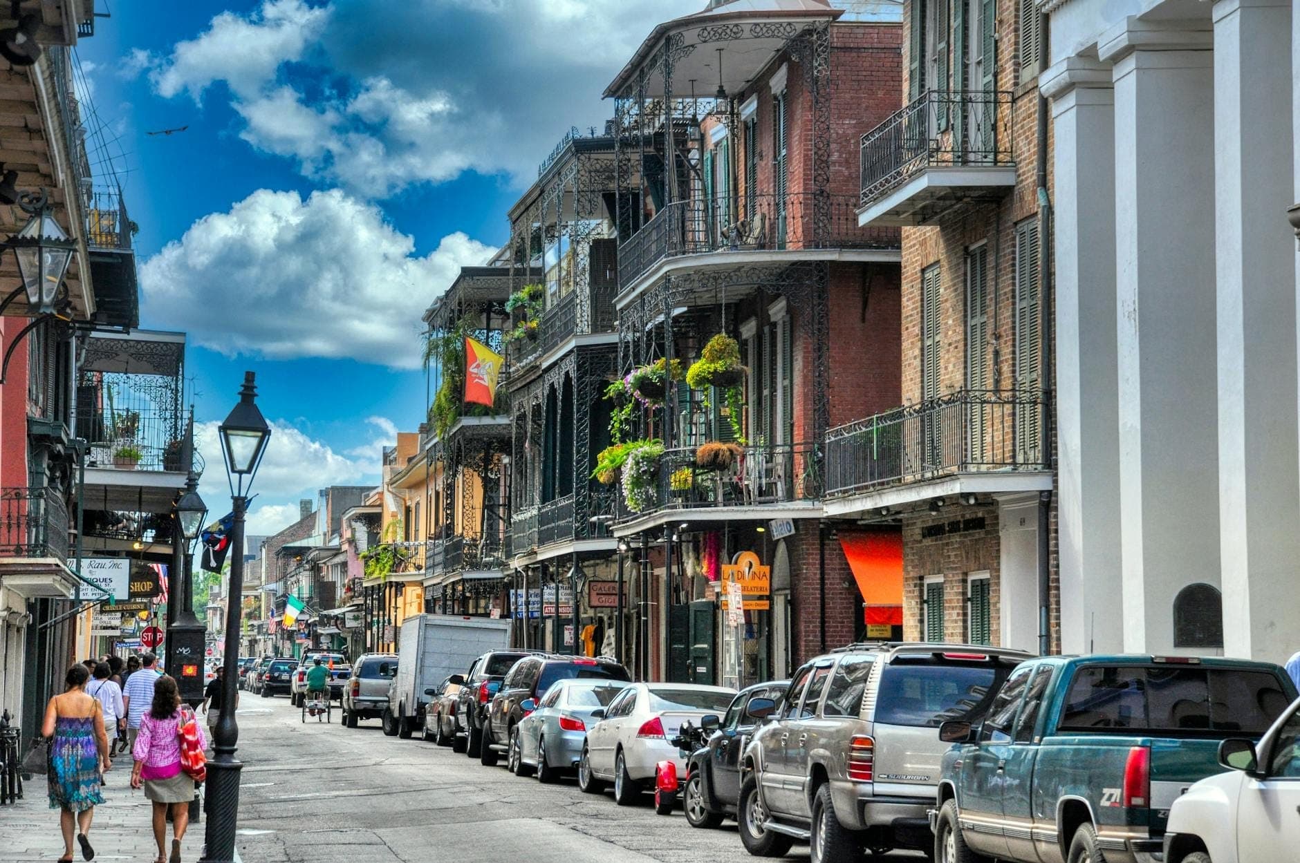 ผู้คนเดินเล่นบนถนนประวัติศาสตร์ที่คึกคักใน New Orleans พร้อมระเบียงอันเป็นเอกลักษณ์และอาคารสีสันสดใส