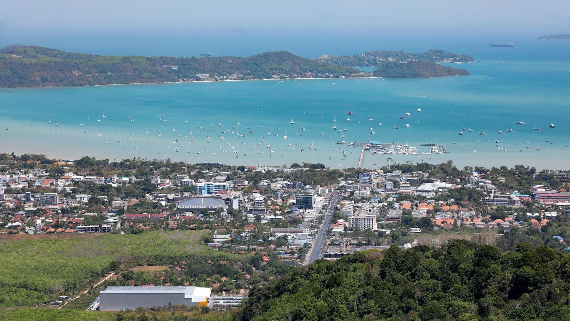 Vista aérea de Phuket con la ciudad, la carretera principal, la costa y el terreno montañoso que se une a la bahía.