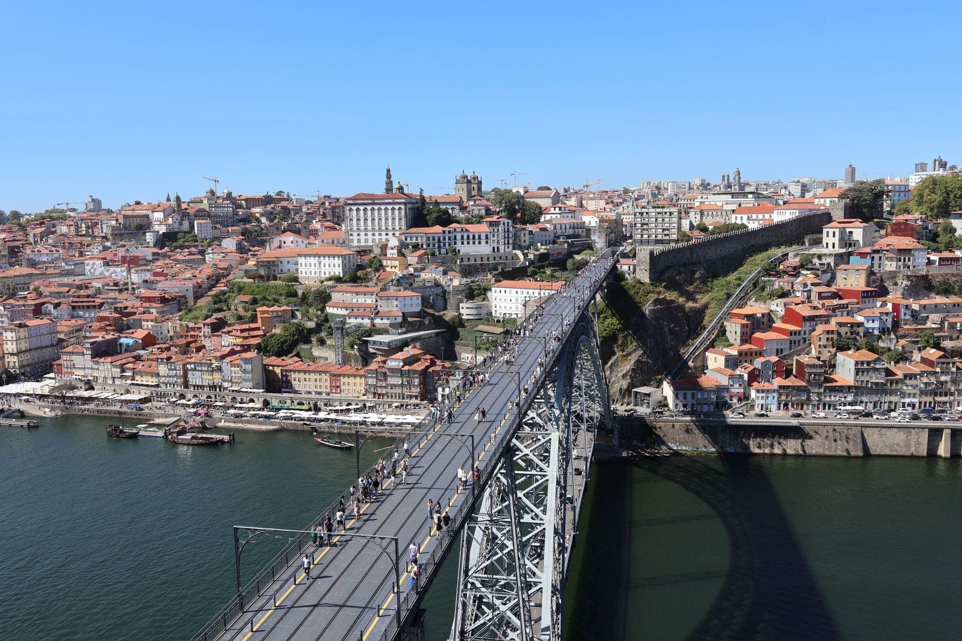 Una nitida vista diurna di Porto con l'iconica Ponte Dom Luís I, il fiume Douro e il paesaggio urbano collinare della città.