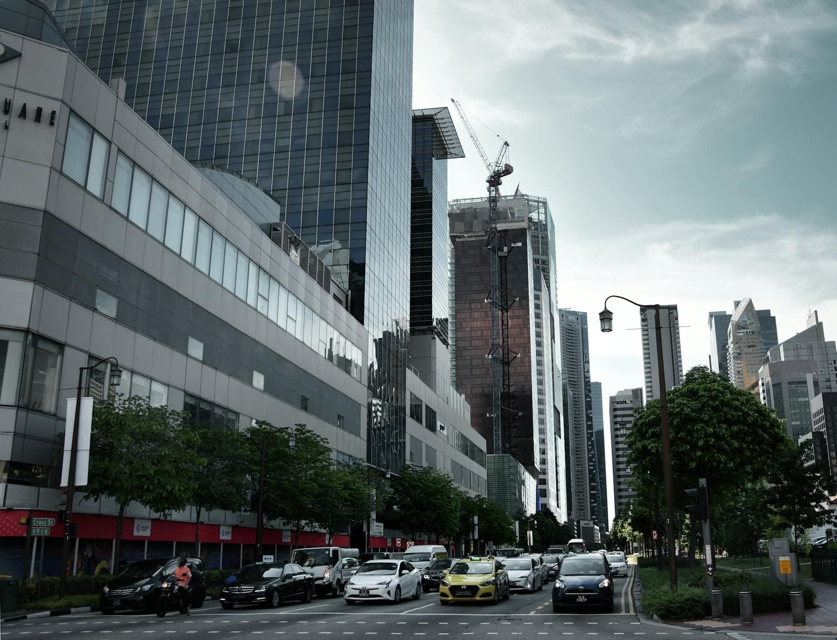 Stadtstraße in Singapur mit modernen Gebäuden und einem gelben Taxi unter anderen fahrenden Autos, das den städtischen Verkehr veranschaulicht.