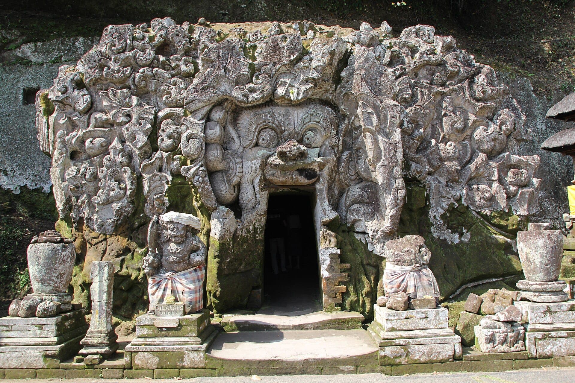 Intricate stone carvings of demons and mythical creatures adorn the menacing entrance to Goa Gajah Elephant Cave in Bali.