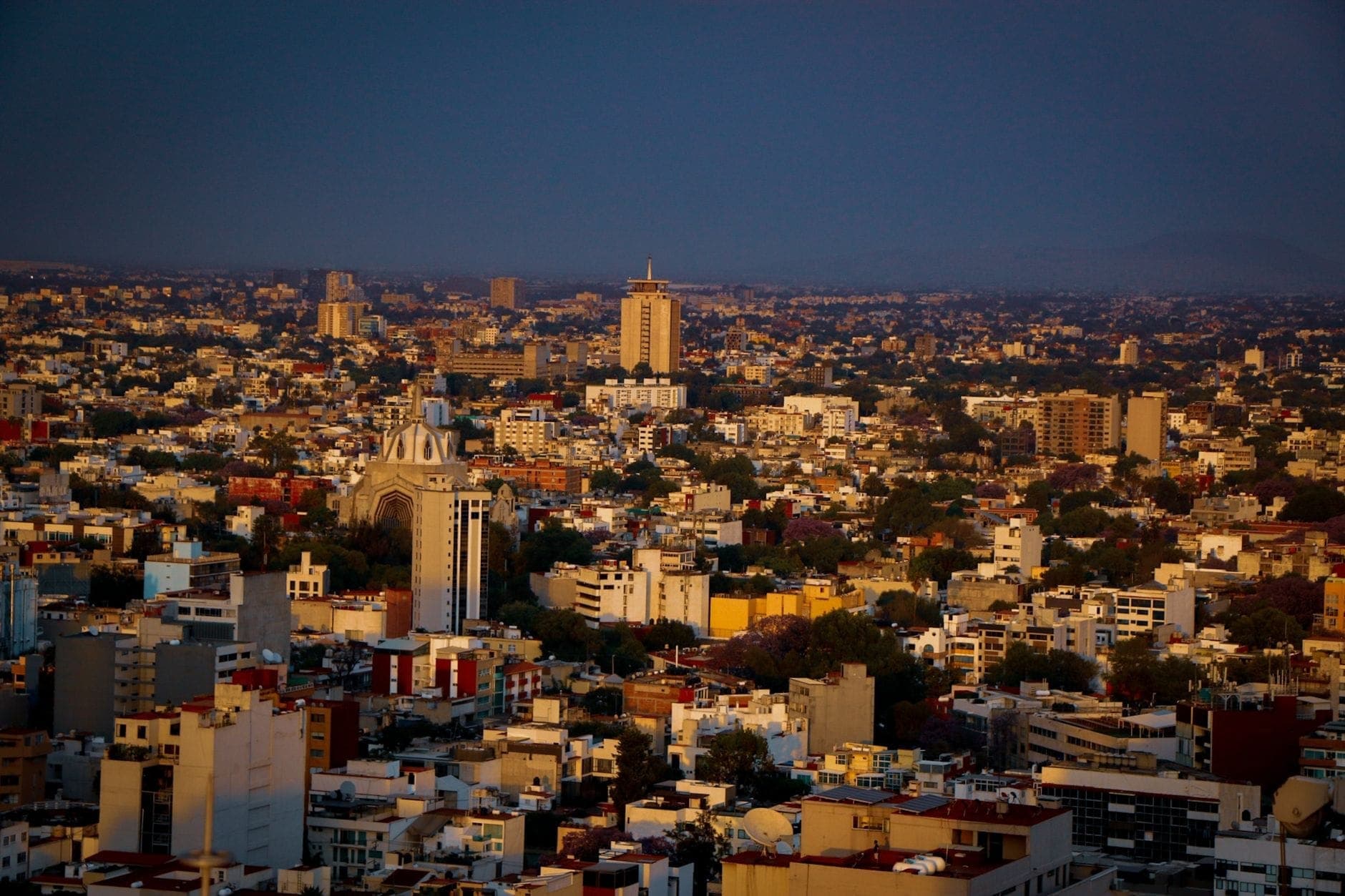 วิวพาโนรามากว้างของเส้นขอบฟ้าเมือง Guadalajara ที่มีการพัฒนาเมืองอย่างหนาแน่นและอาคารสำคัญ ถ่ายในช่วงพระอาทิตย์ตกดินใต้ท้องฟ้าที่ดูดราม่า