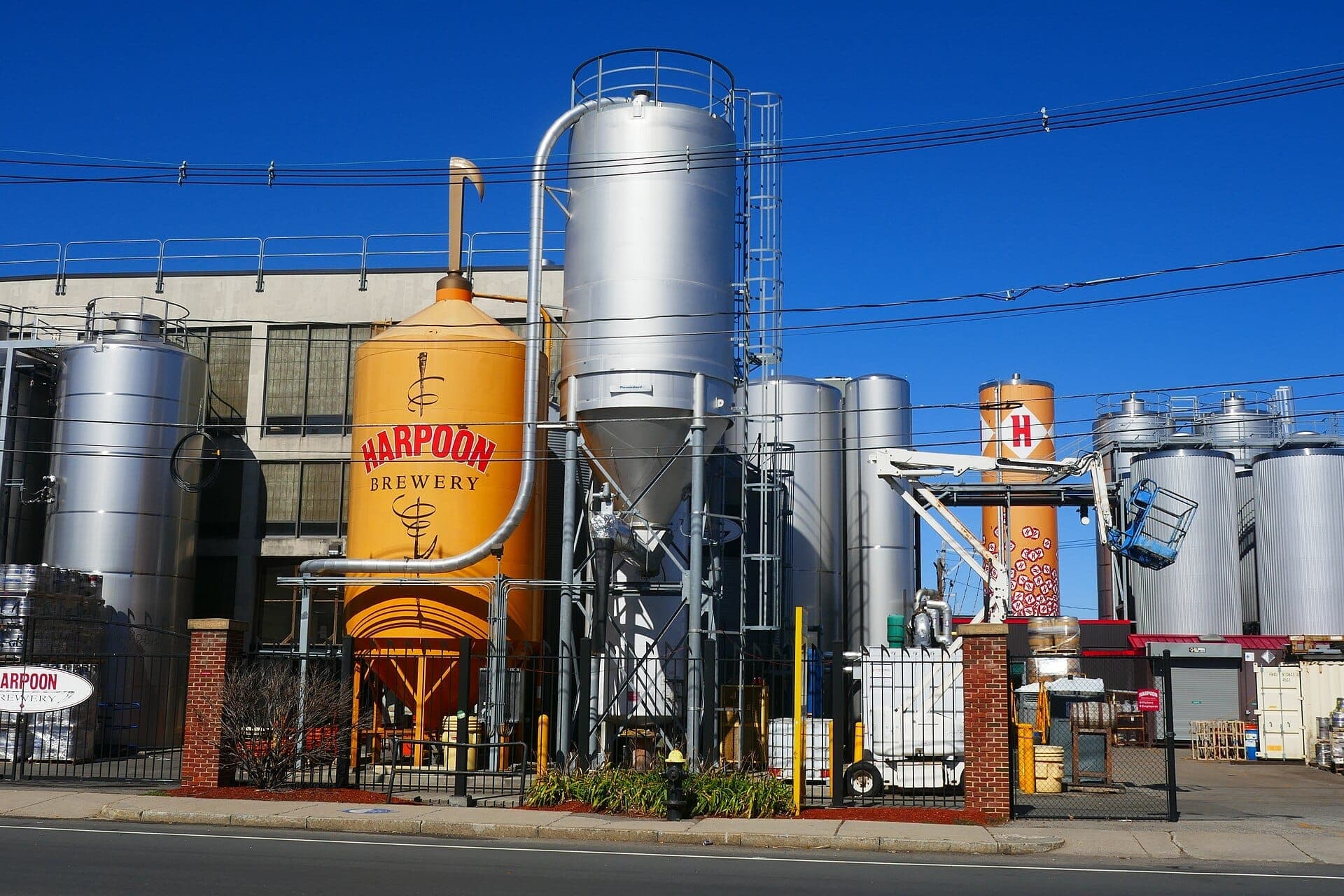 Extérieur de la Harpoon Brewery avec de grands cuves de brassage et des silos en acier inoxydable par une journée ensoleillée dans le Seaport District de Boston.