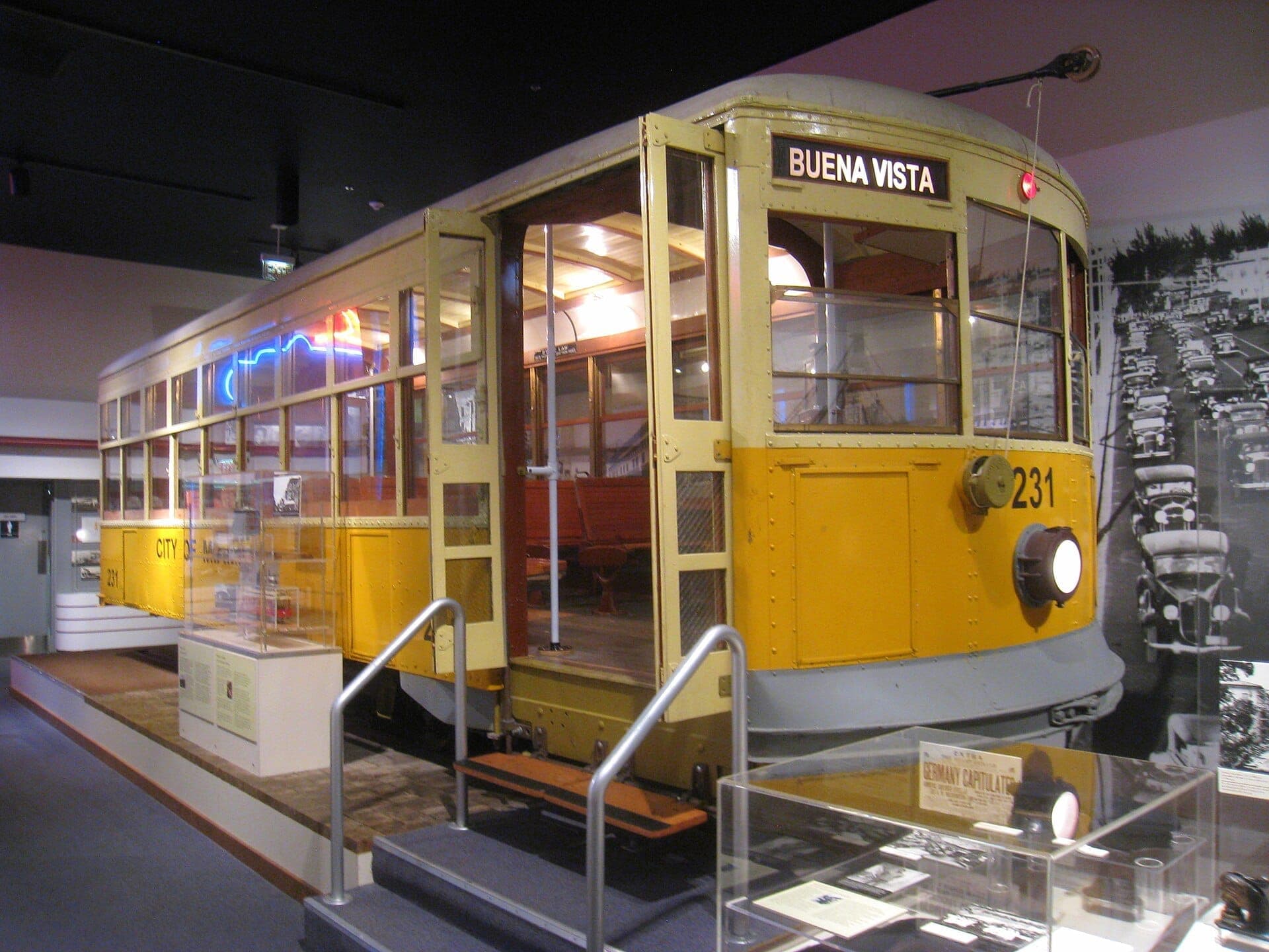Historic yellow streetcar display at Museum of Miami, surrounded by vintage photos and artifacts in a well-lit exhibition space.
