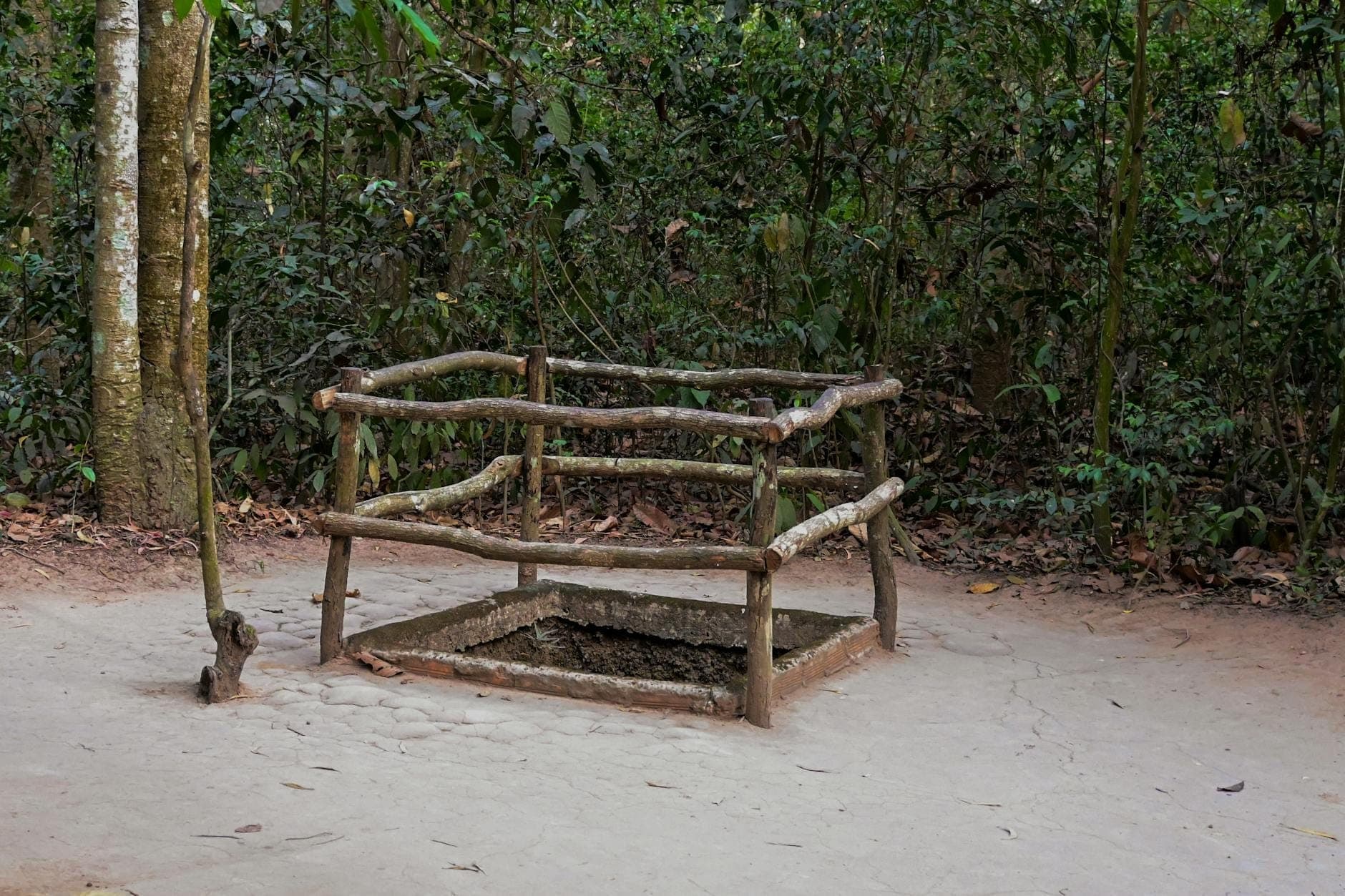 Uma entrada camuflada para os Túneis de Cu Chi cercada por uma cerca de madeira, situada em uma área arborizada perto de Ho Chi Minh City.