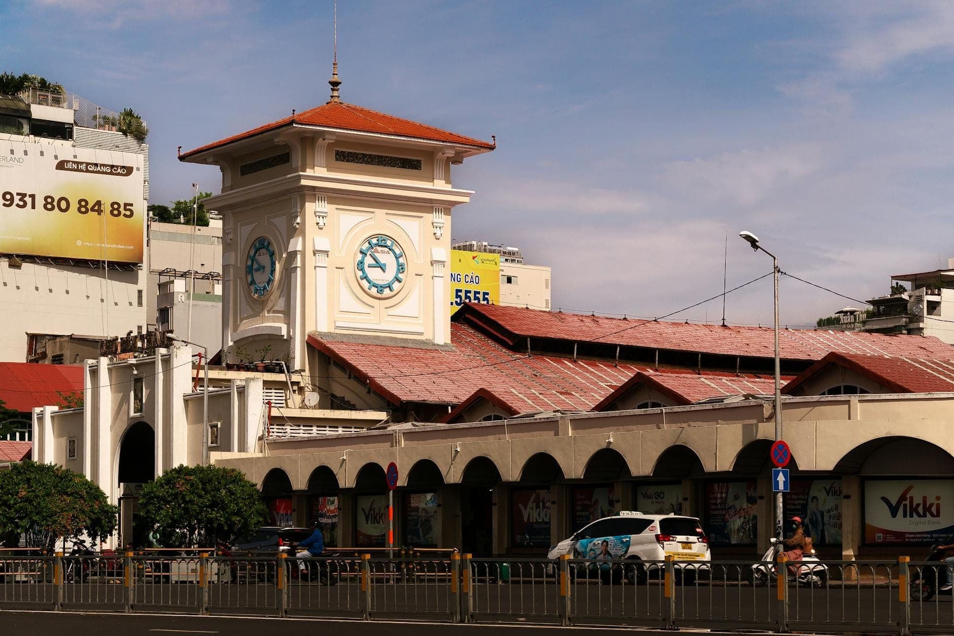 Mặt ngoài chợ Bến Thành vào ban ngày với tháp đồng hồ đặc trưng và con đường tấp nập xung quanh tại Thành phố Hồ Chí Minh.