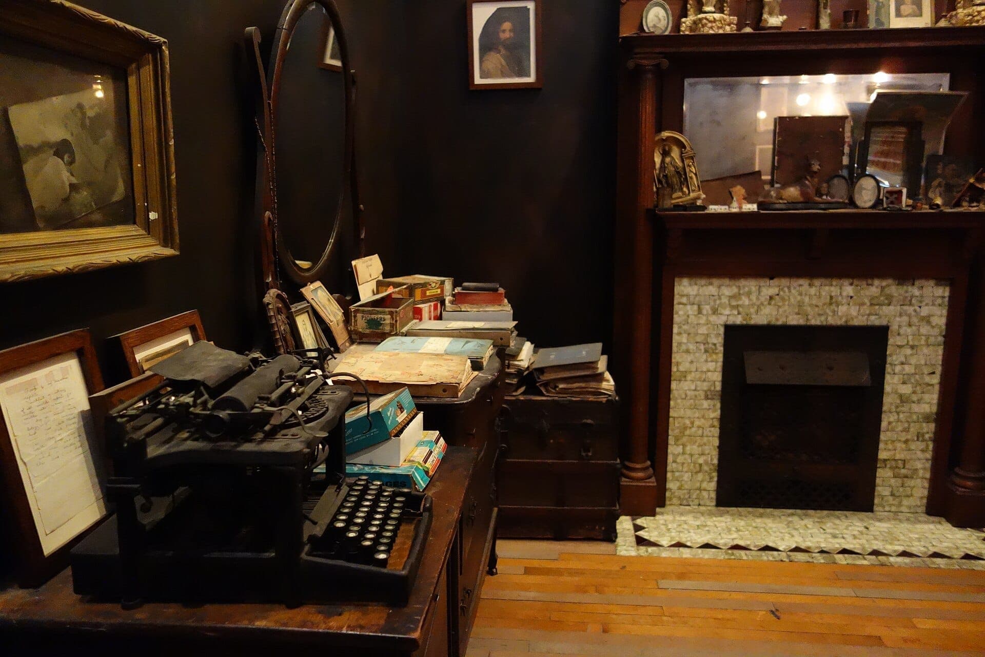 Antique typewriter, stacked vintage books, and framed photos fill the dimly lit Henry Darger room inside the Intuit Art Museum in Chicago.