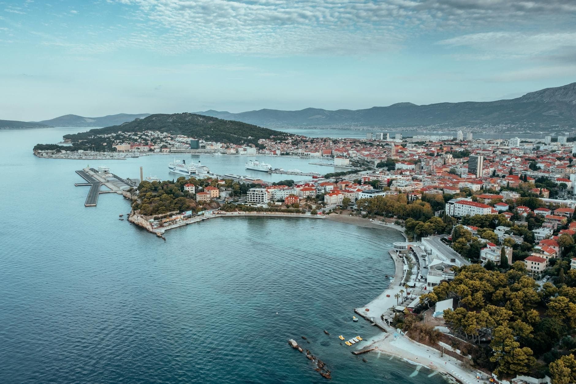 Vista aerea di Spalato, Croazia, con la costa, il porto, i moli dei traghetti e gli edifici della città con le montagne sullo sfondo.
