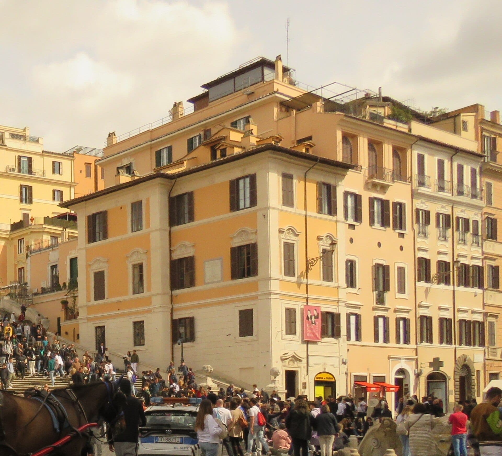 Ang Keats-Shelley House sa Roma, isang panghistoriyang gusaling kulay rosas na pitsas sa paanan ng Spanish Steps, napapalibutan ng mga bisita sa isang maliwanag na araw.