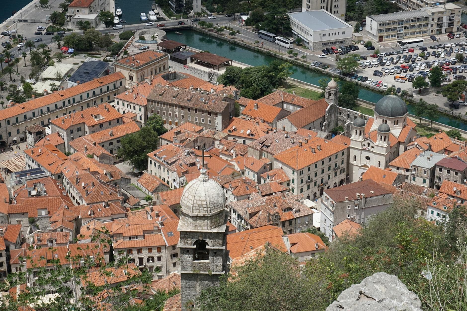 Vue aérienne de la vieille ville de Kotor avec ses toits de tuiles oranges, ses bâtiments historiques, ses églises et ses fortifications médiévales.