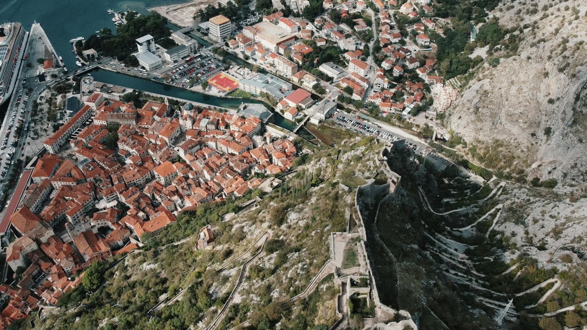 Vue aérienne saisissante de la vieille ville de Kotor et des remparts qui zigzaguent sur les pentes abruptes du mont Saint-Jean, révélant les fortifications surplombant la baie adriatique.