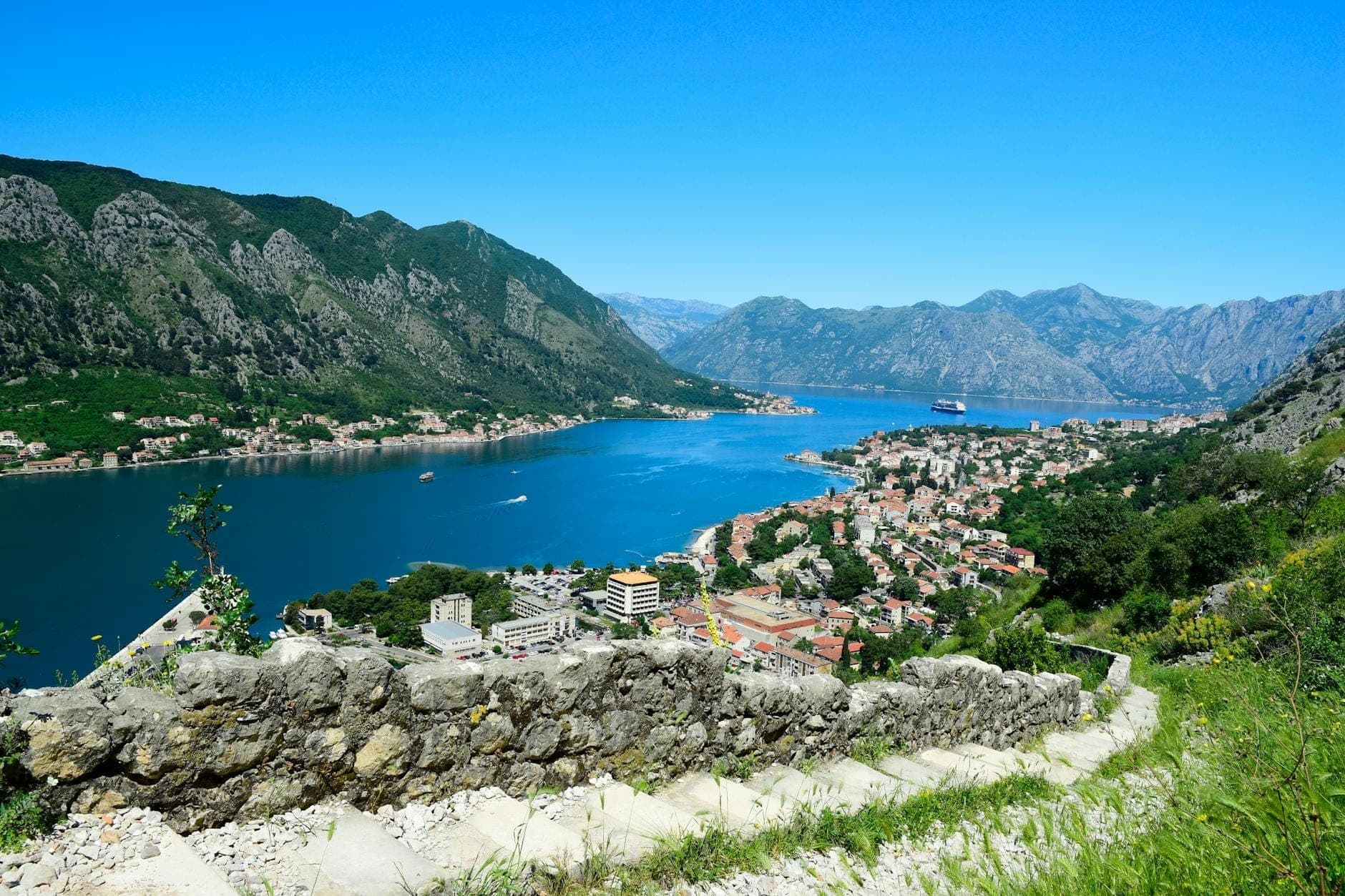 Vue panoramique depuis la Forteresse de Kotor surplombant la Baie de Kotor, la ville et les montagnes environnantes par une journée ensoleillée et claire.