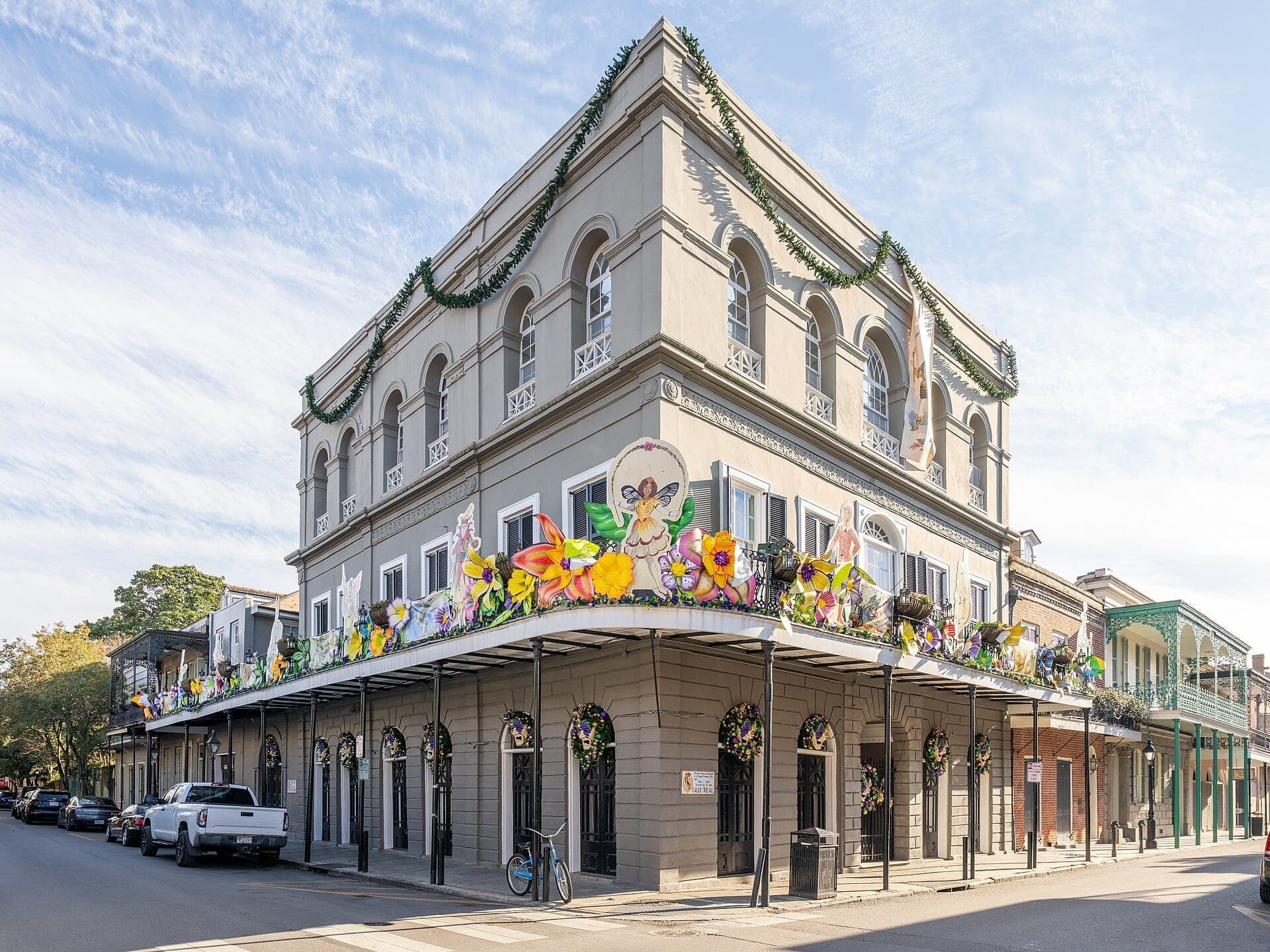 View of the historic LaLaurie Mansion in New Orleans, a three-story gray building with arched windows and festive flower decorations on the balcony.