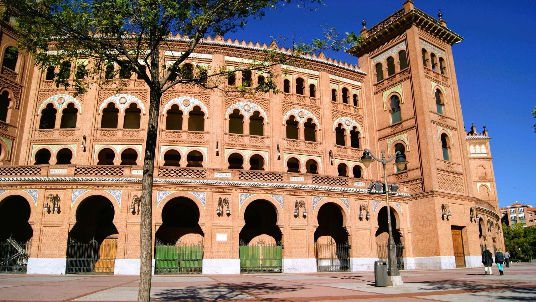 อาคารอิฐสไตล์ Neo-Mudéjar ของ Plaza de Toros de Las Ventas ในมาดริด โดนแสงแดดส่อง เผยหน้าต่างโค้งกับท้องฟ้าสีฟ้าใส