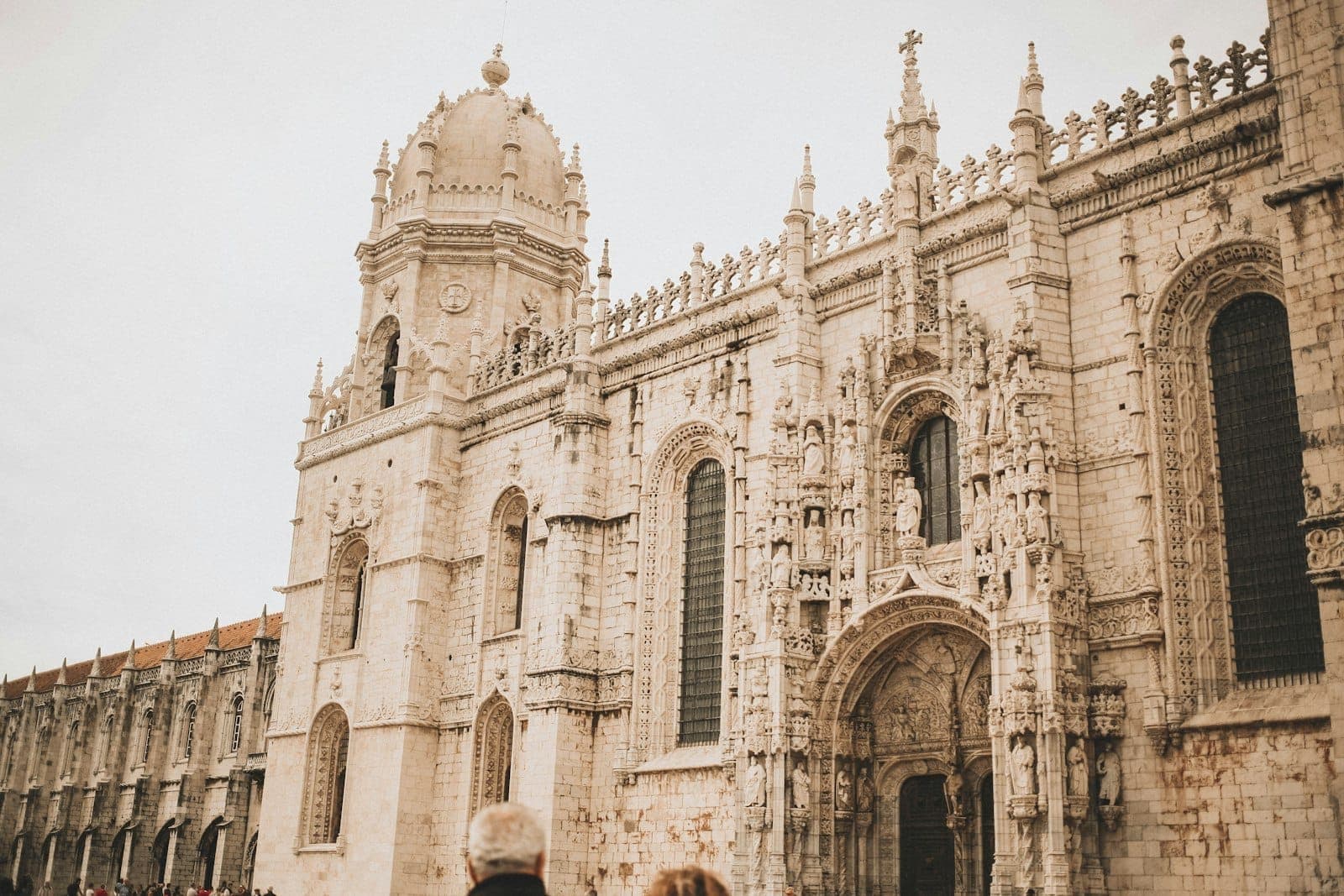 Vista de perto da ornamentada entrada principal e da torre do Mosteiro dos Jerónimos em Belém, Lisboa, com detalhes nítidos da sua arquitetura manuelina.