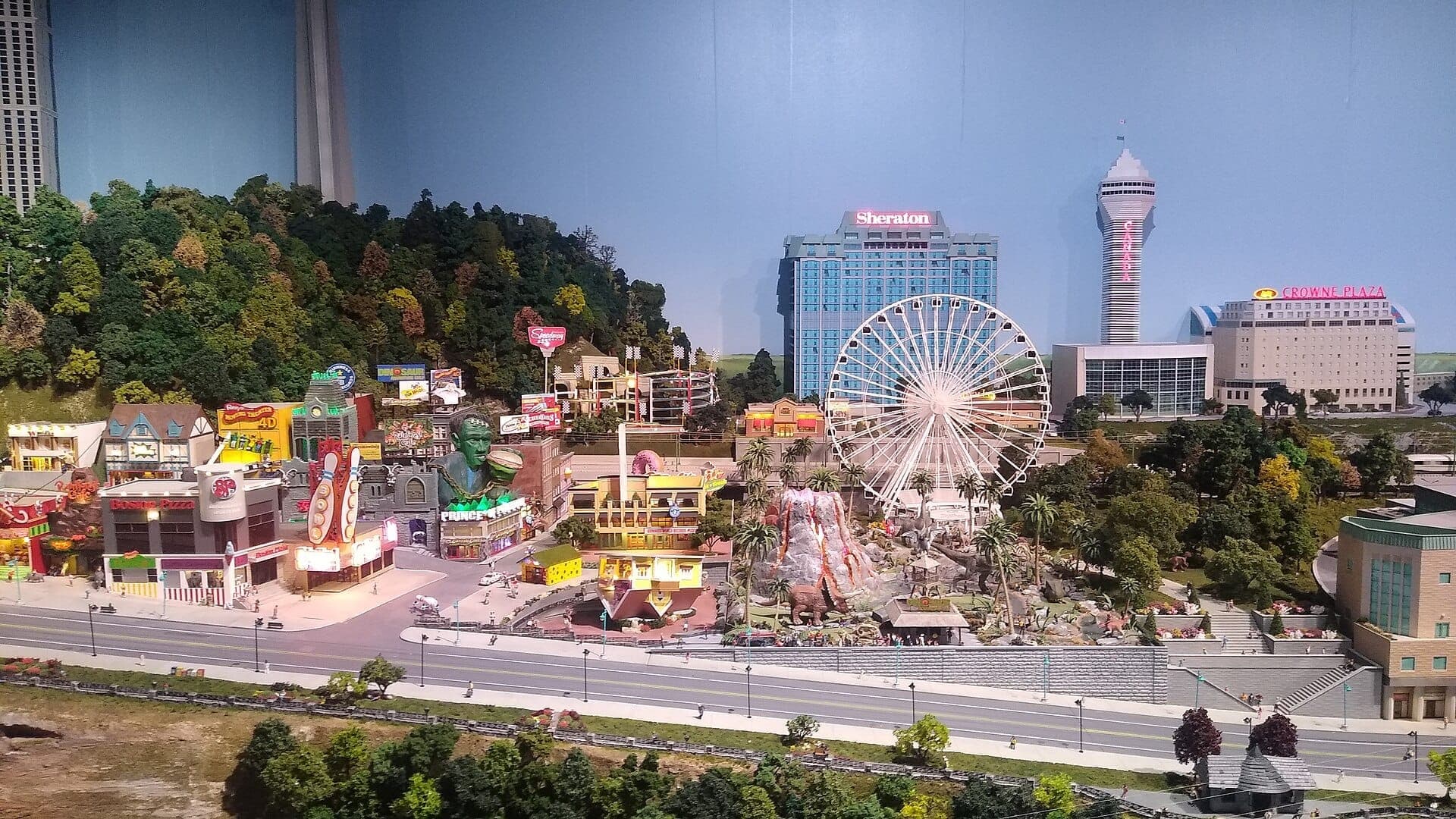 Modello in scala dettagliato di Little Canada Toronto con una grande ruota panoramica, attrazioni vivaci, hotel della città e lussureggianti alberi in miniatura sotto luci brillanti.