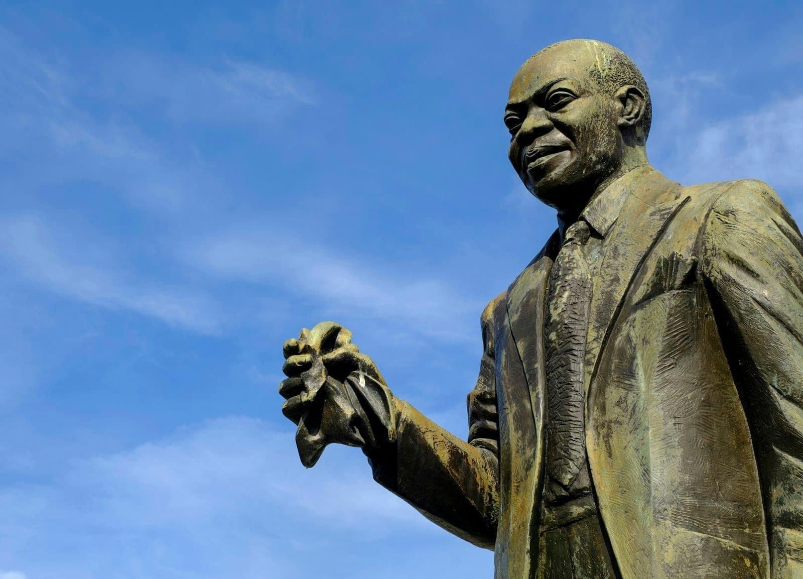Bronze statue of Louis Armstrong in Louis Armstrong Park, New Orleans, set against a bright blue sky.