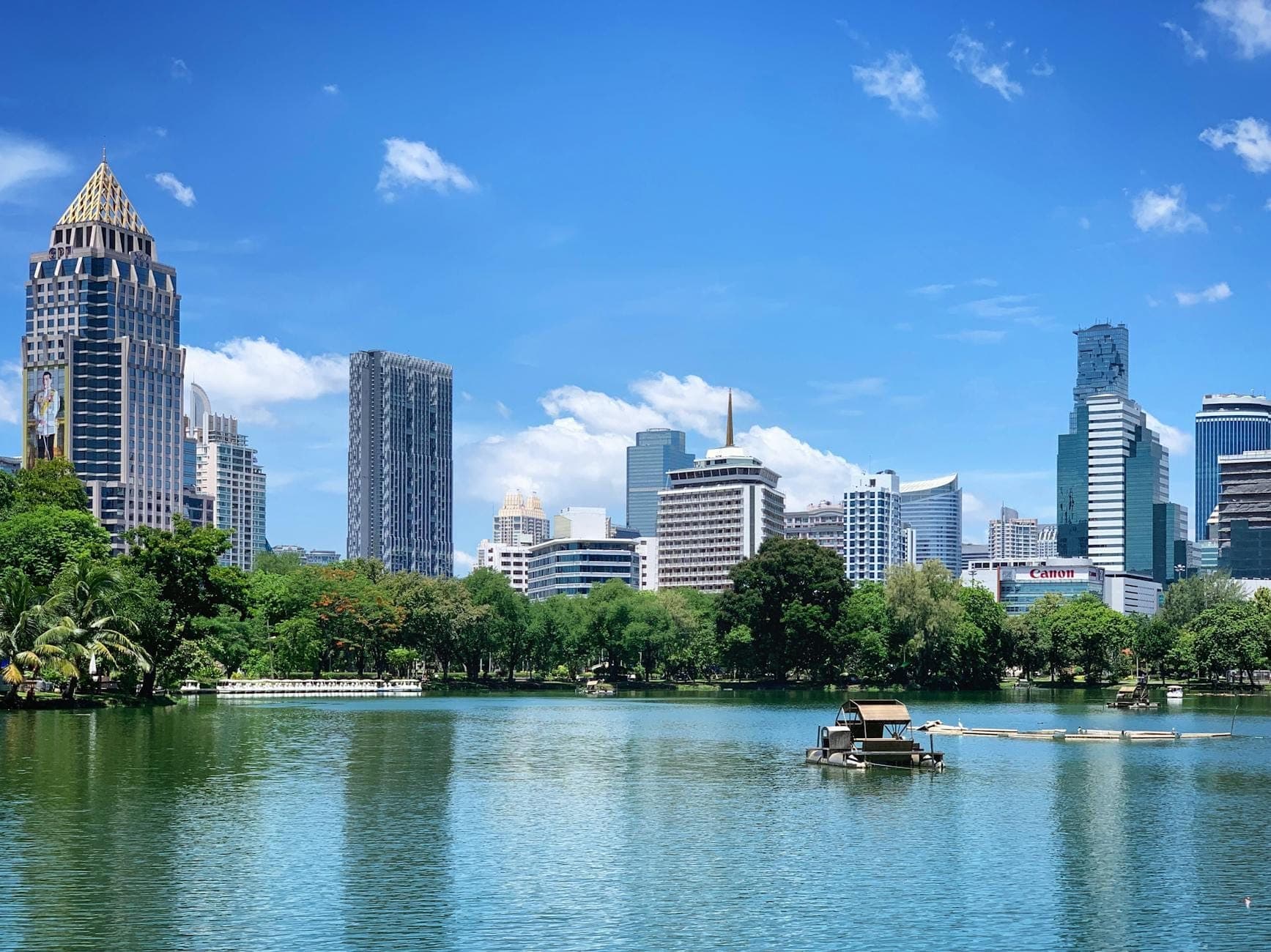 Парк Люмпини в Бангкоке с озером, лодкой и видом на городские небоскрёбы