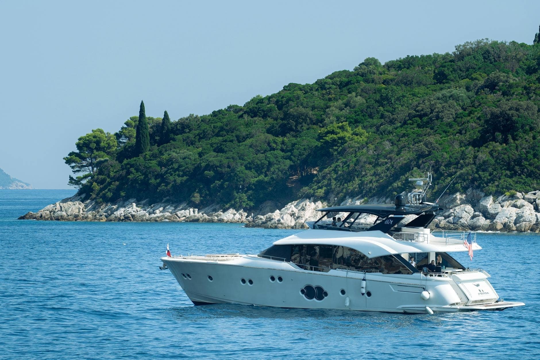 Luxusyacht auf ruhigen blauen Gewässern mit einer üppig begrünten Insel im Hintergrund, die ein exklusives Bootsabenteuer in Dubrovnik veranschaulicht.