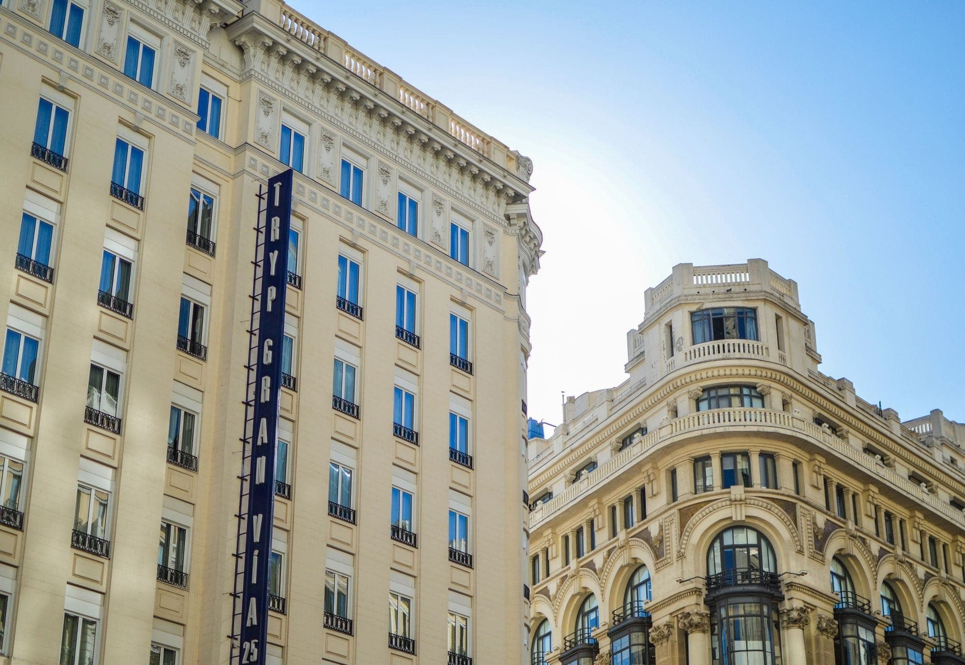 Elegante facciata dell'Hotel Gran Via a Madrid con la sua architettura classica sotto un cielo azzurro limpido.