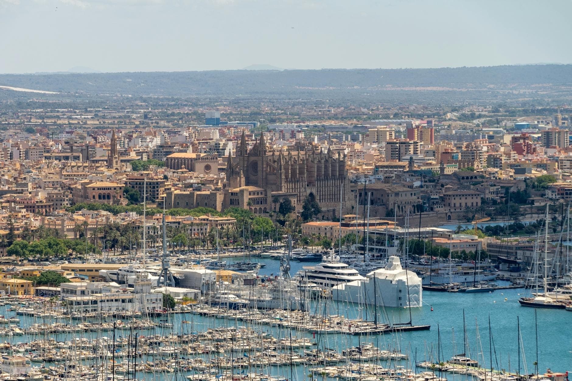 ภาพทางอากาศของ Palma de Mallorca พร้อมเรือยอชต์หรูในมารีน่า ทัศนียภาพเมือง และมหาวิหารในพื้นหลังใต้ท้องฟ้าแจ่มใส