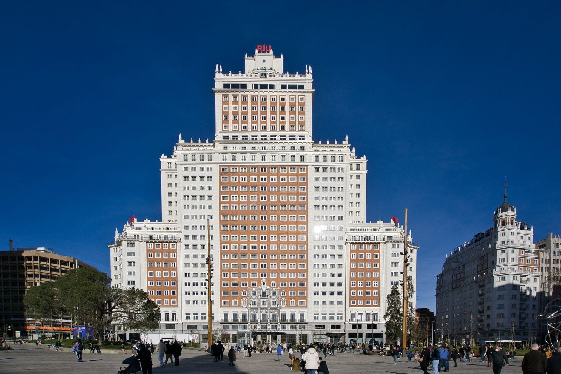 Front view of the Edificio España in Madrid, a monumental post-war skyscraper with a stepped silhouette against a clear blue sky.