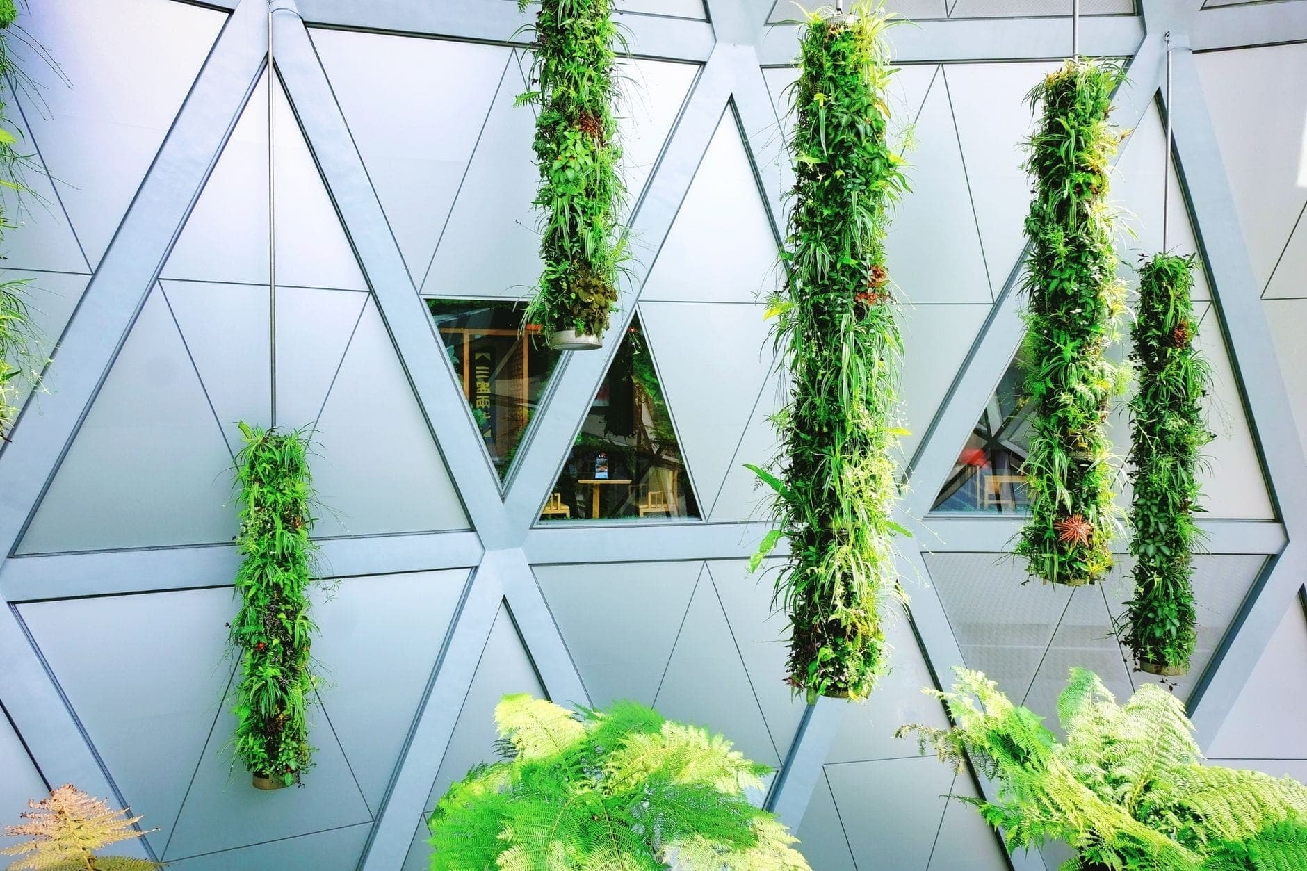 Modern building facade in Madrid with geometric triangular panels and hanging vertical gardens, showcasing contemporary architectural design.
