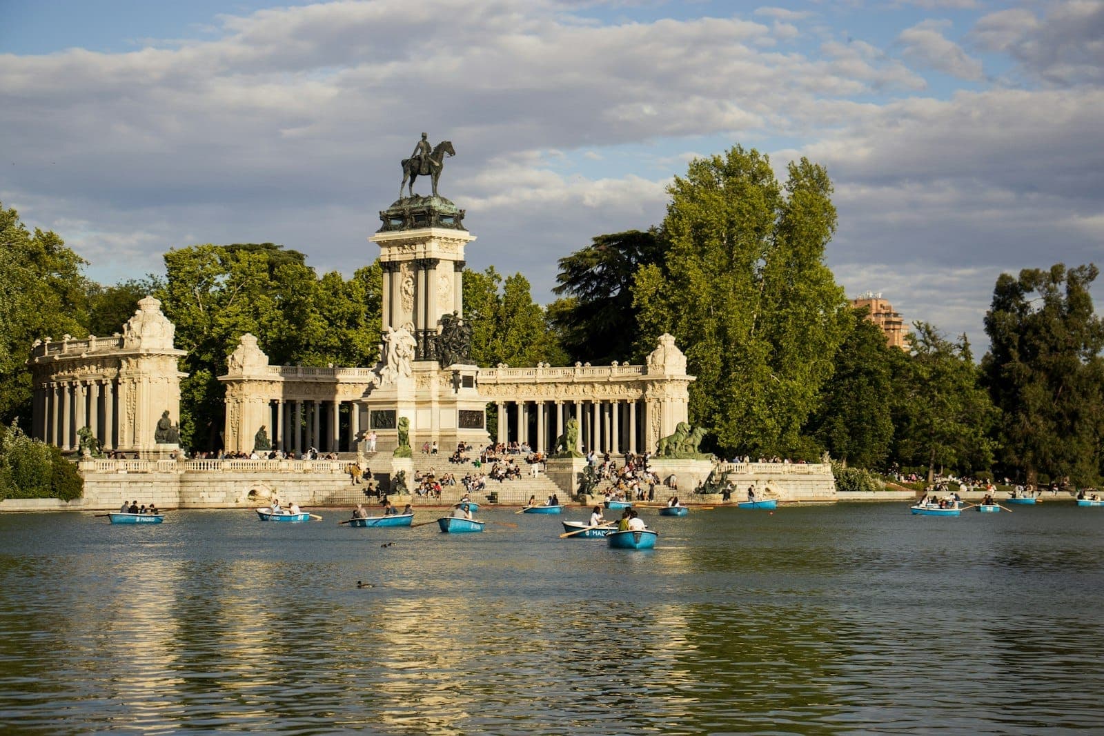 Persone in barca sul lago principale di fronte al monumento ad Alfonso XII nel Parque El Retiro a Madrid in una giornata di sole.