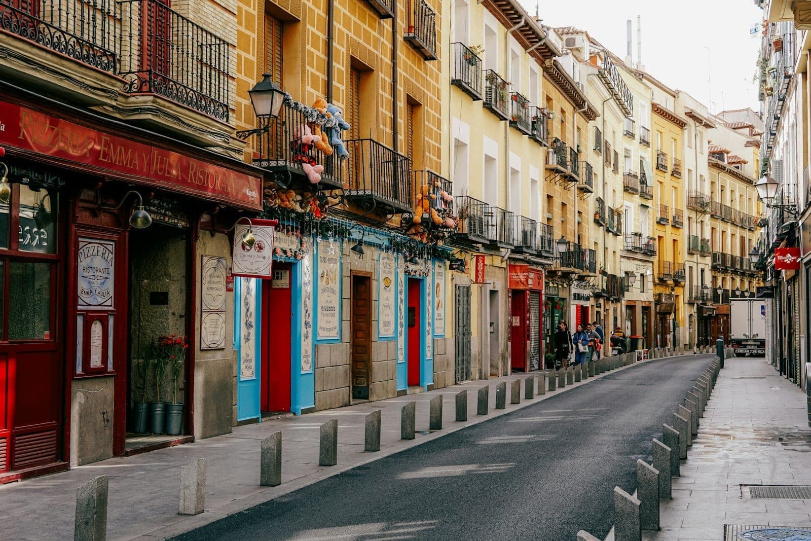 Stradina colorata e stretta di Madrid fiancheggiata da caffè, bar e negozi locali in un quartiere tranquillo, senza folla e con la luce del mattino.