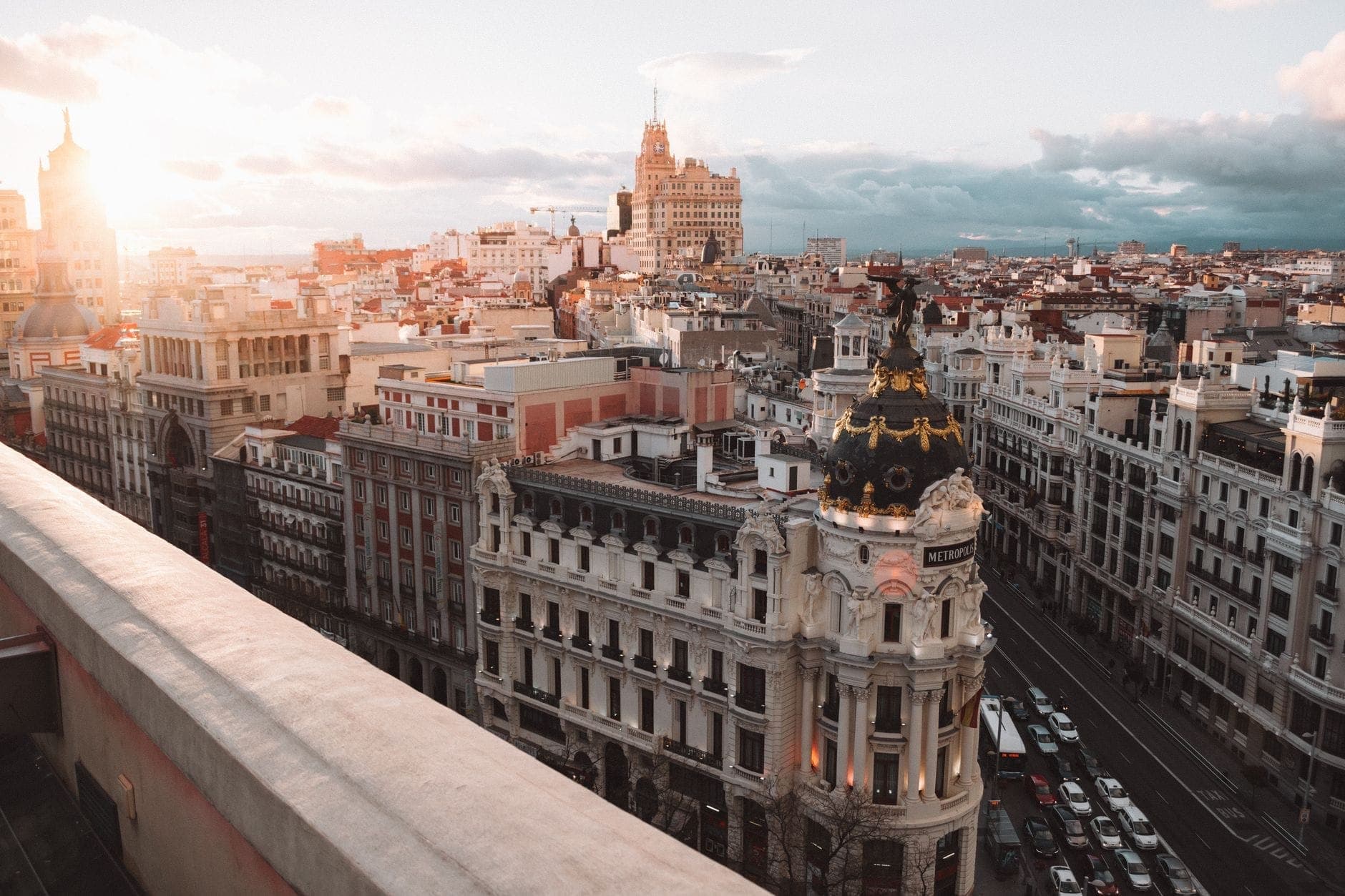 Vista aerea della Gran Vía di Madrid con l'iconico edificio Metropolis alla luce del sole e il paesaggio urbano che si estende fino all'orizzonte.