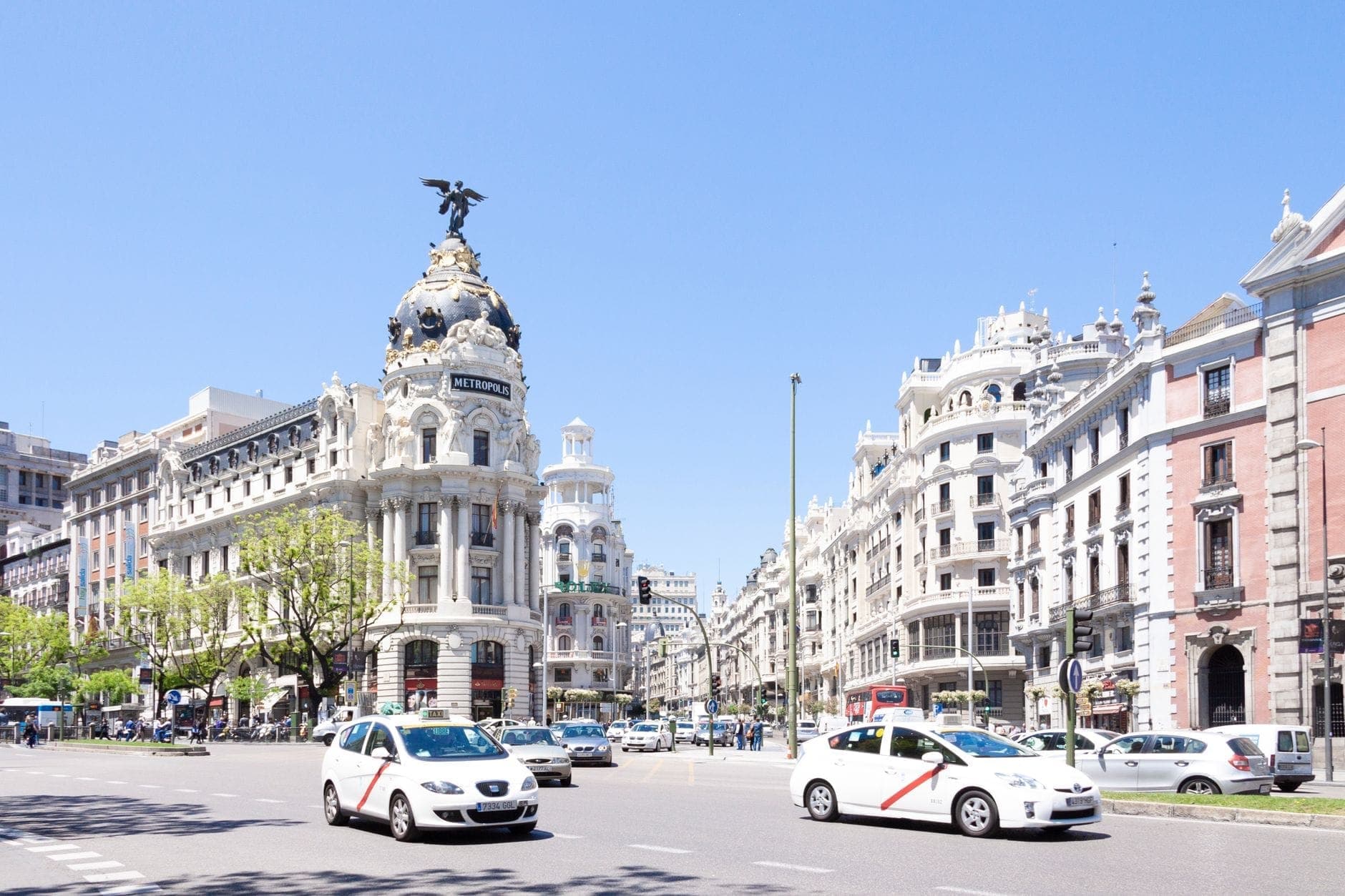 วิวกว้างถนน Gran Via อันเป็นสัญลักษณ์ของมาดริด มีตึกสวยคลาสสิก รถราแน่นขนัด และท้องฟ้าสดใส สะท้อนชีวิตเมืองคึกคักและสถาปัตยกรรมประวัติศาสตร์