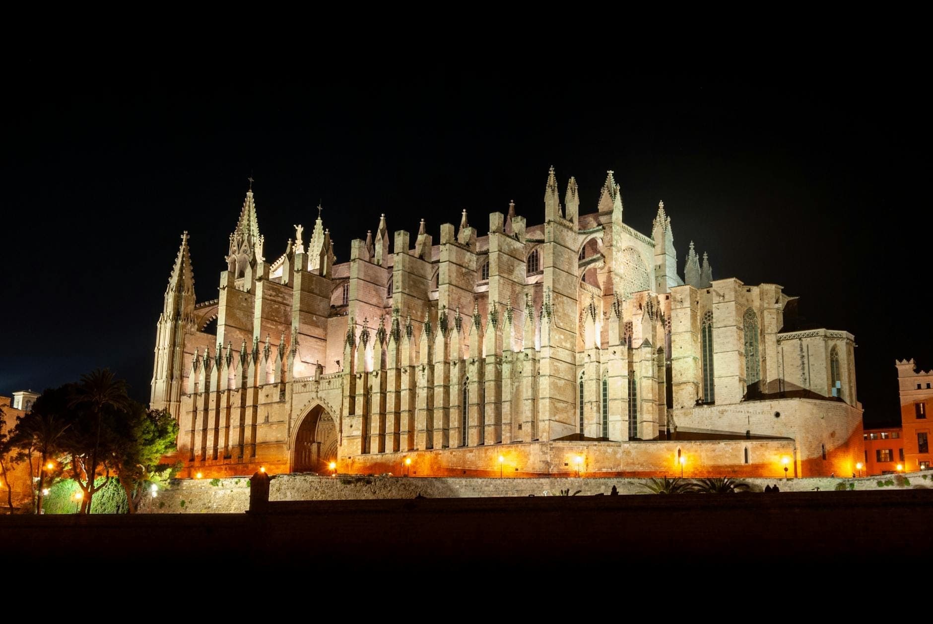 La Cattedrale La Seu a Palma de Mallorca illuminata di notte con luci suggestive su uno sfondo di cielo scuro.