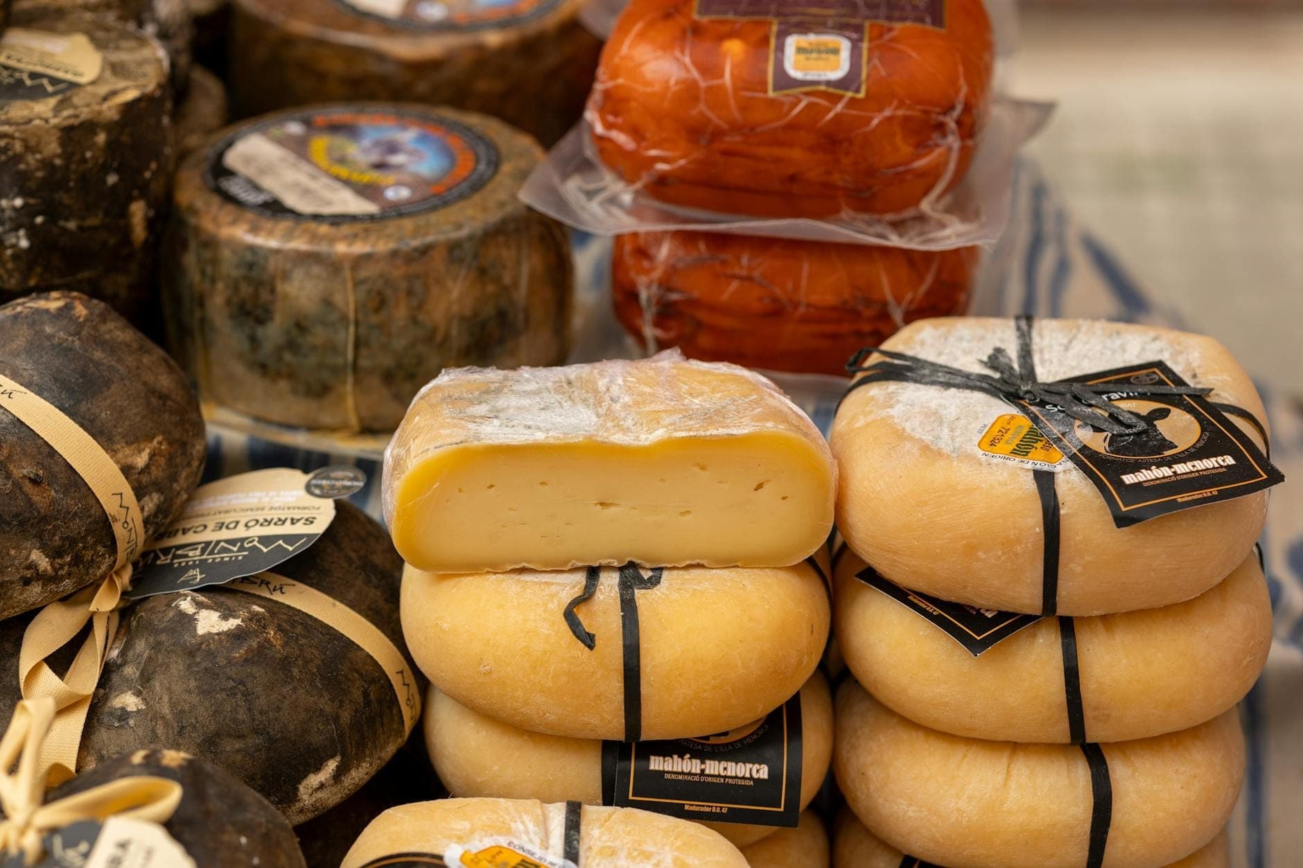 Primo piano di formaggi locali di Mallorca avvolti ed esposti su un tavolo di mercato, pronti all'acquisto come autentici prodotti regionali.