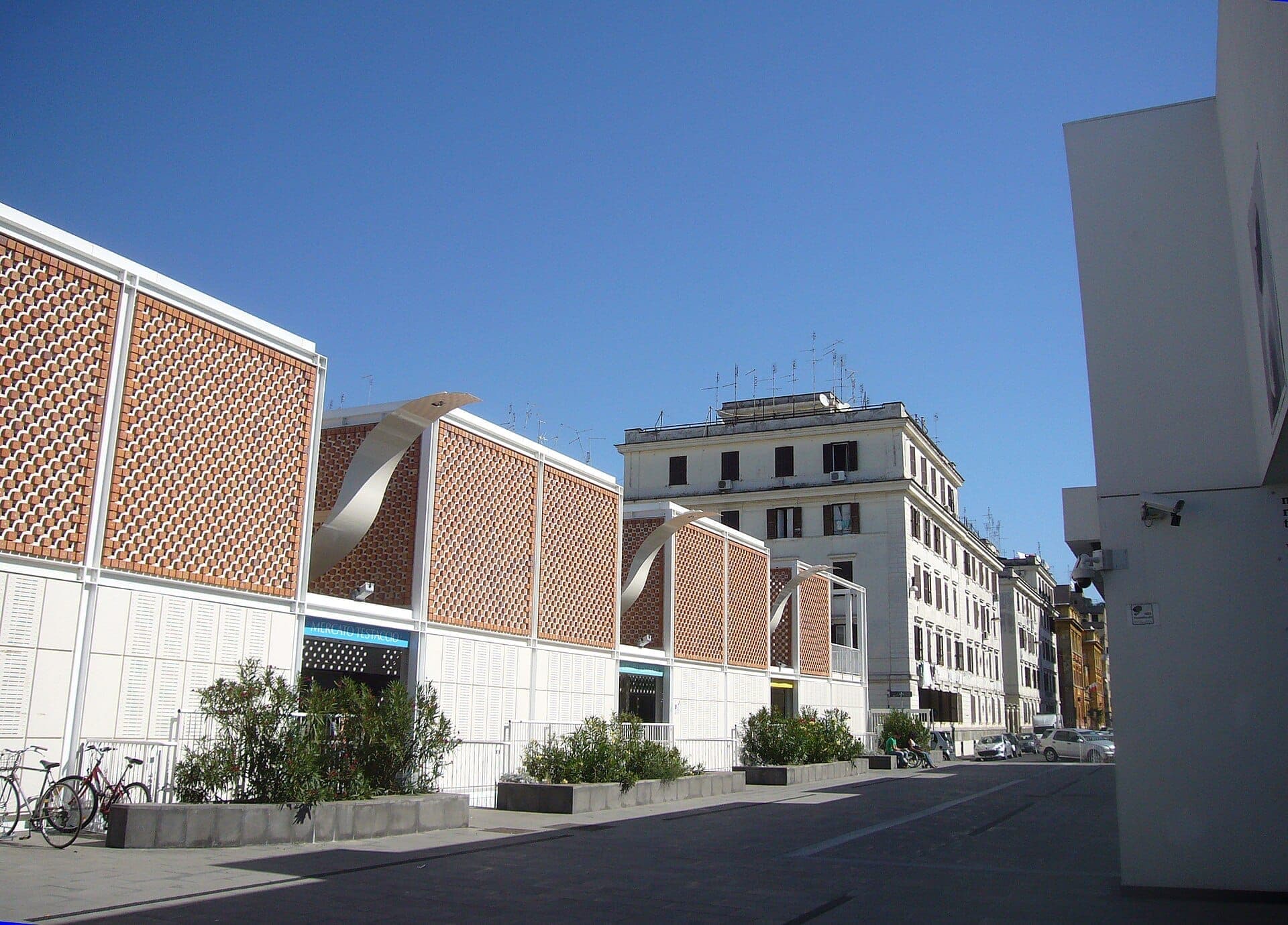 Esterno del Nuovo Mercato di Testaccio a Roma con moderna architettura a griglia in mattoni sotto un cielo azzurro limpido e gli edifici circostanti della città.